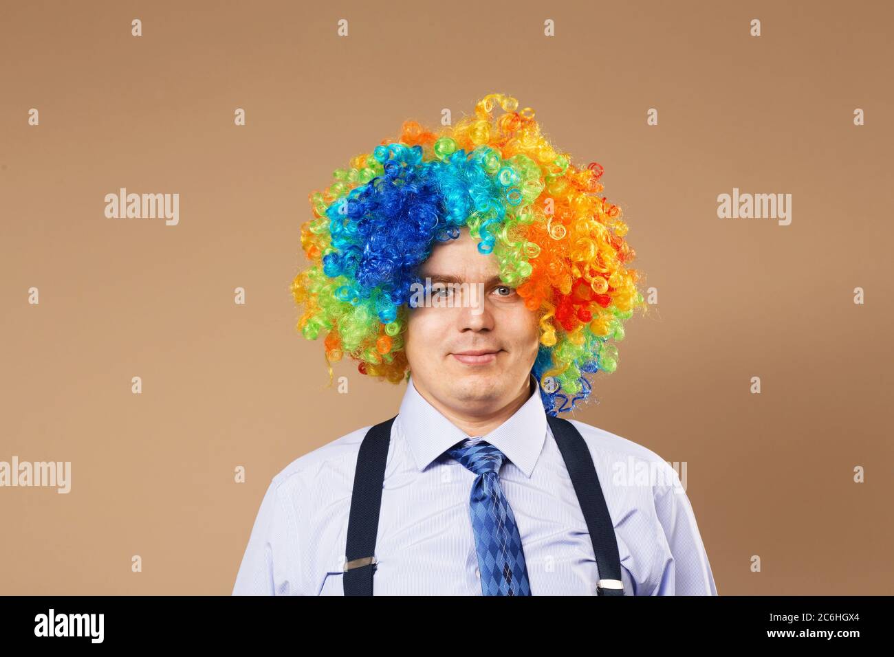 Hombre de negocios sonriente con una peluca grande y colorida. Primer plano  Retrato de hombre de negocios en peluca payaso. Concepto de negocio  Fotografía de stock - Alamy