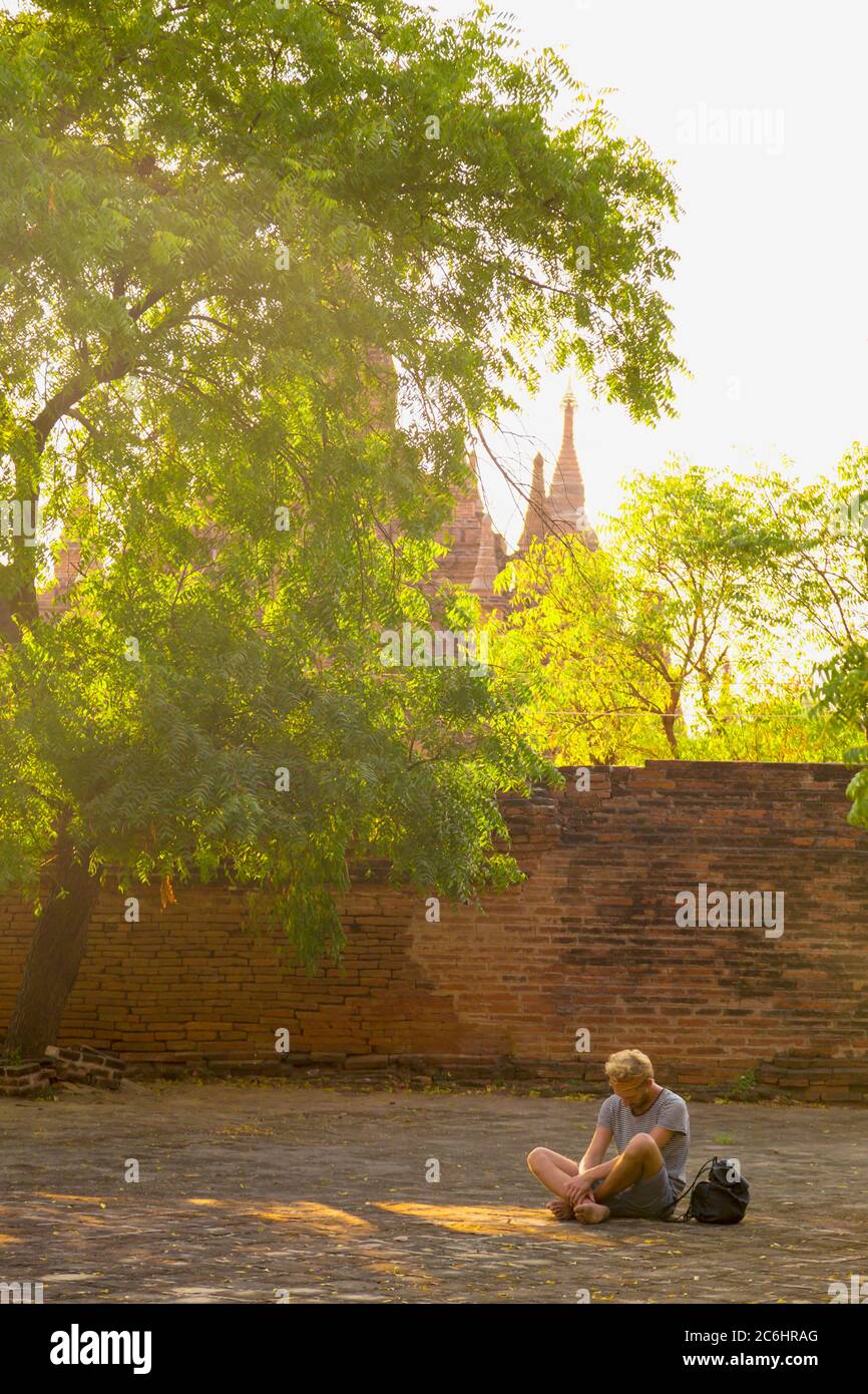 Un joven medita fuera de un templo en el Viejo Bagan, Myanmar Foto de stock