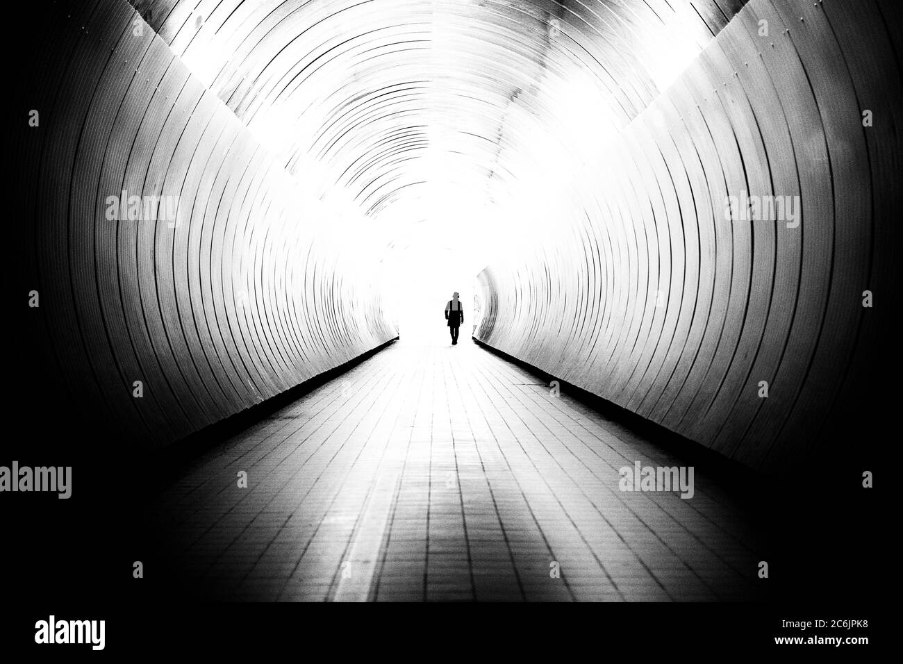 Perspectiva decreciente del hombre irreconocible en un brillante túnel público en Estocolmo, Suecia. El túnel es un camino entre dos calles. Foto de stock