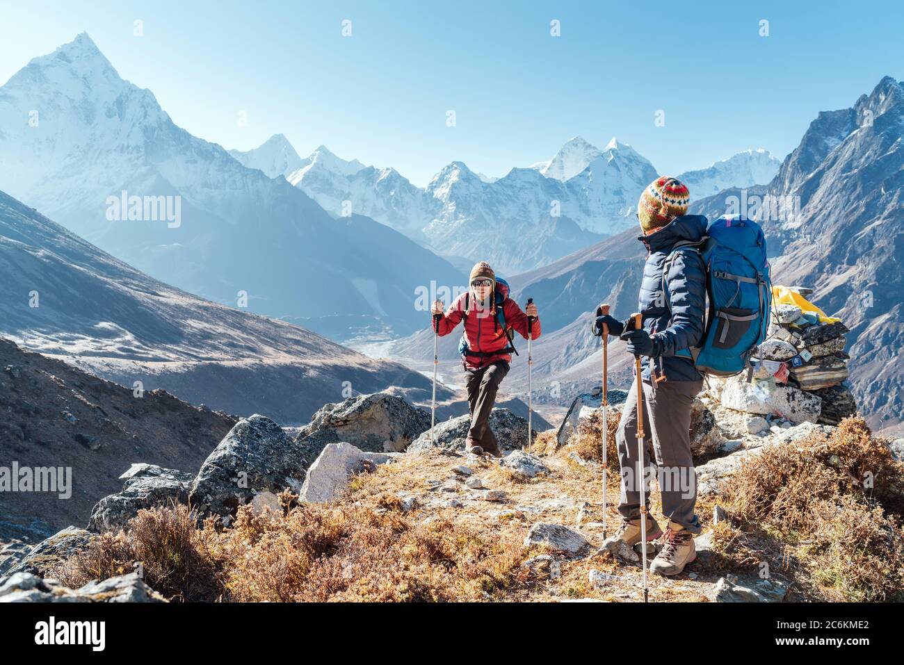 Pareja siguiendo la ruta de senderismo Everest base Camp cerca de Dughla 4620m. Backpackers llevar mochilas y utilizando bastones de senderismo y disfrutar de la vista del valle Foto de stock
