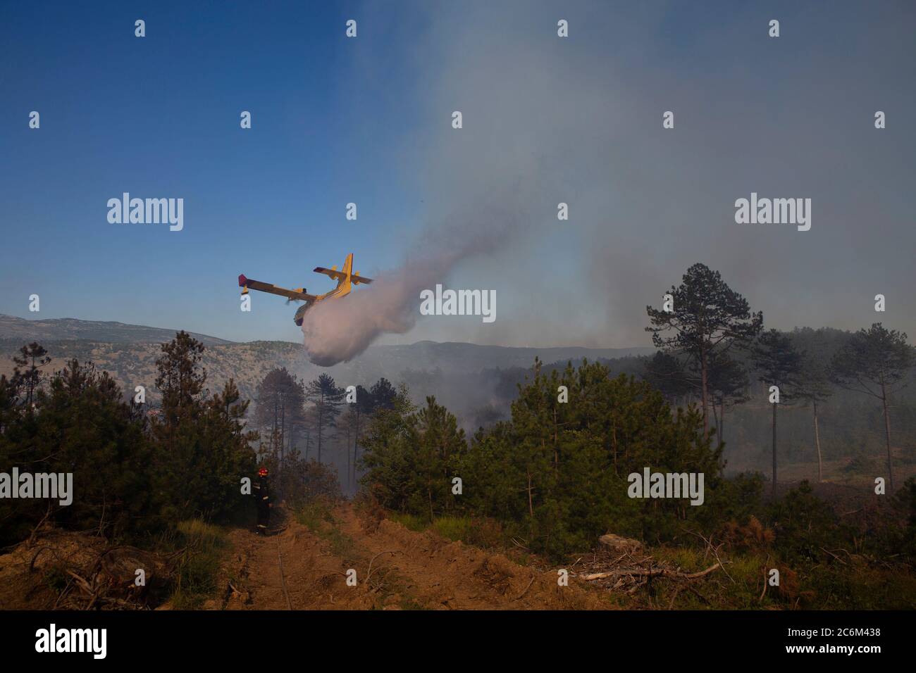 (200711) -- RAMLJANI, 11 de julio de 2020 (Xinhua) -- UN avión vierte agua en fuego durante un esfuerzo por apagar un incendio forestal cerca de la aldea de Ramljani en el condado central de Lika-Senj, en Croacia, el 10 de julio de 2020. El incendio comenzó en la región montañosa el jueves. (Frano Jerkan/Pixsell via Xinhua) Foto de stock