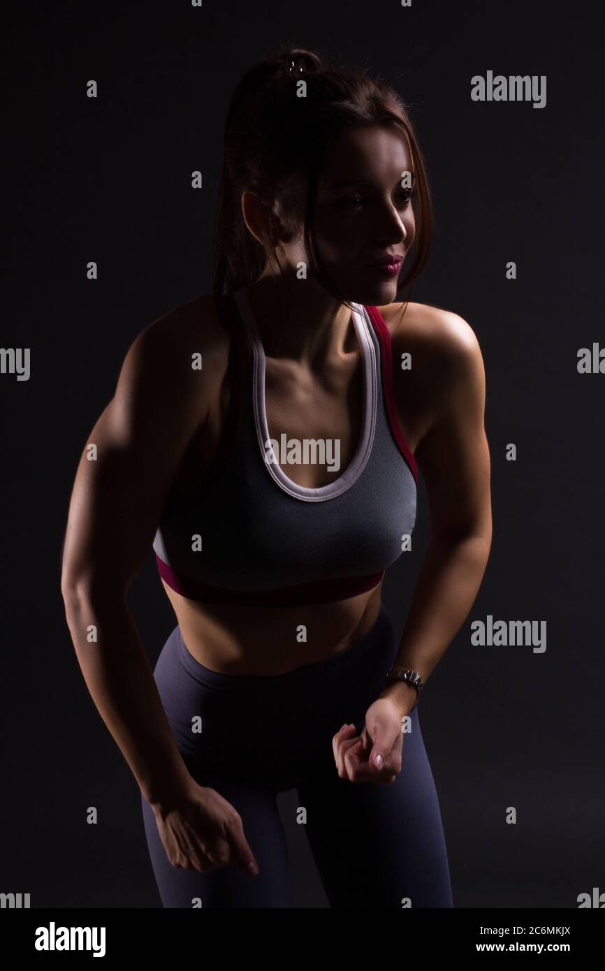 Fitness mujer joven en ropa de entrenamiento, colores oscuros retroiluminado foto Foto de stock