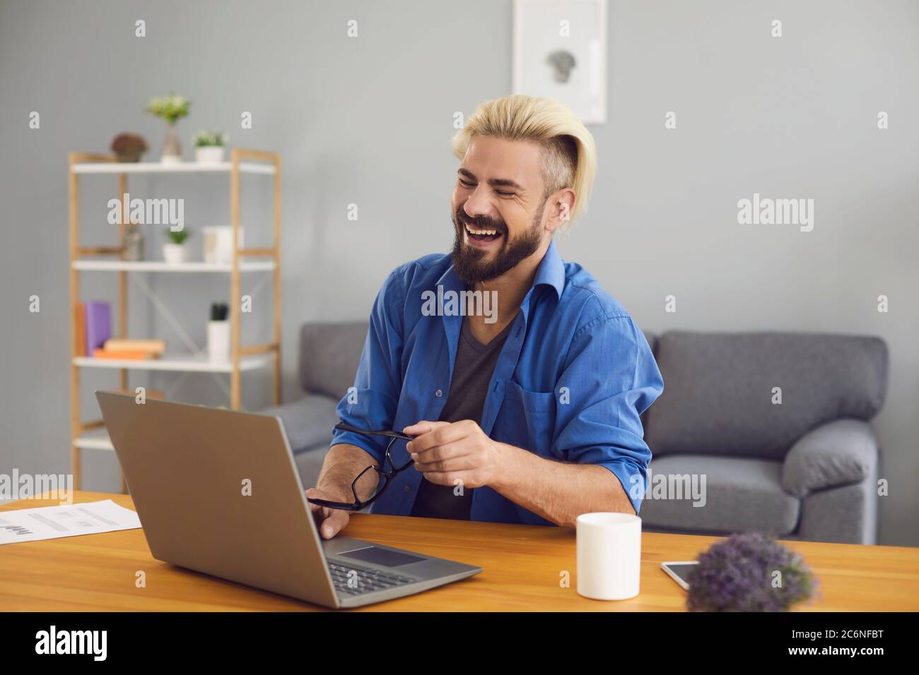 El hombre libre riendo usando el portátil vide conferencia de chat en casa. Foto de stock