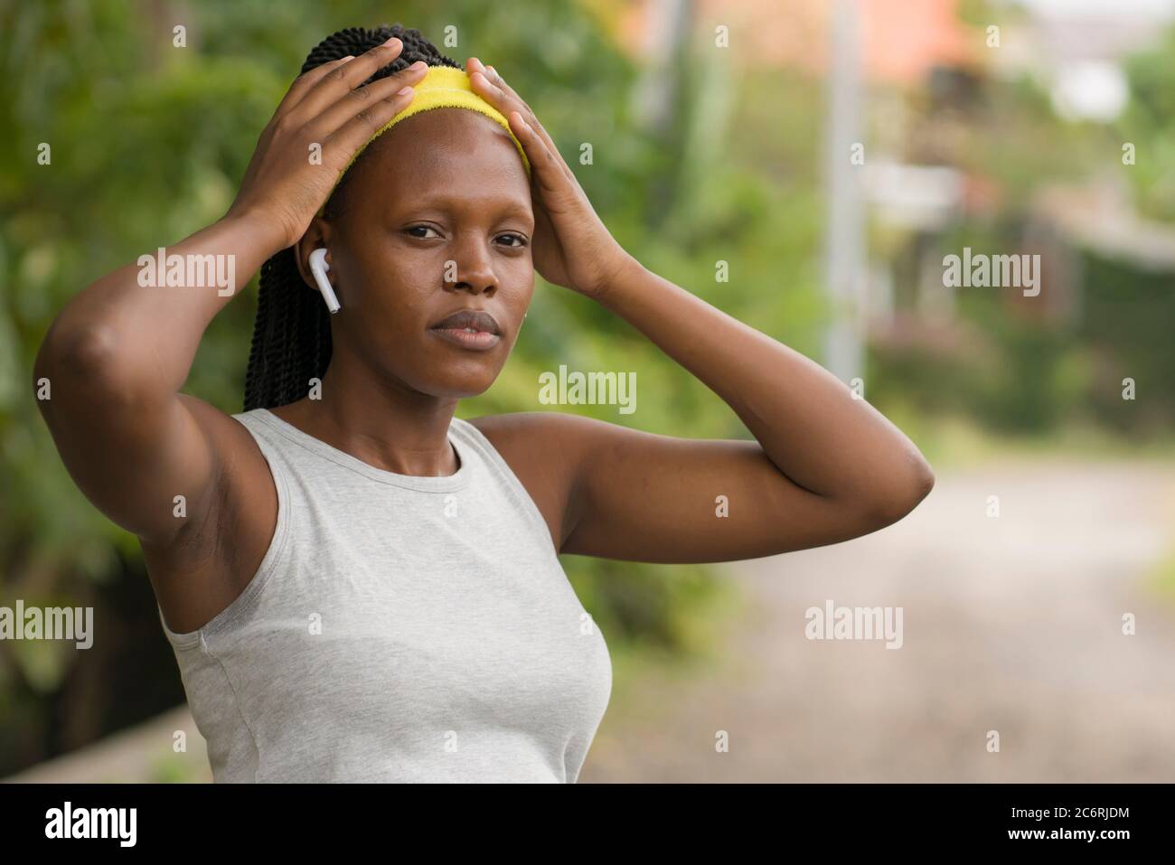 Corredor niña estilo de vida retrato - joven atractivo y ajuste negro afro American mujer ajustar la banda de pelo antes de correr al aire libre entrenamiento en el campo Foto de stock