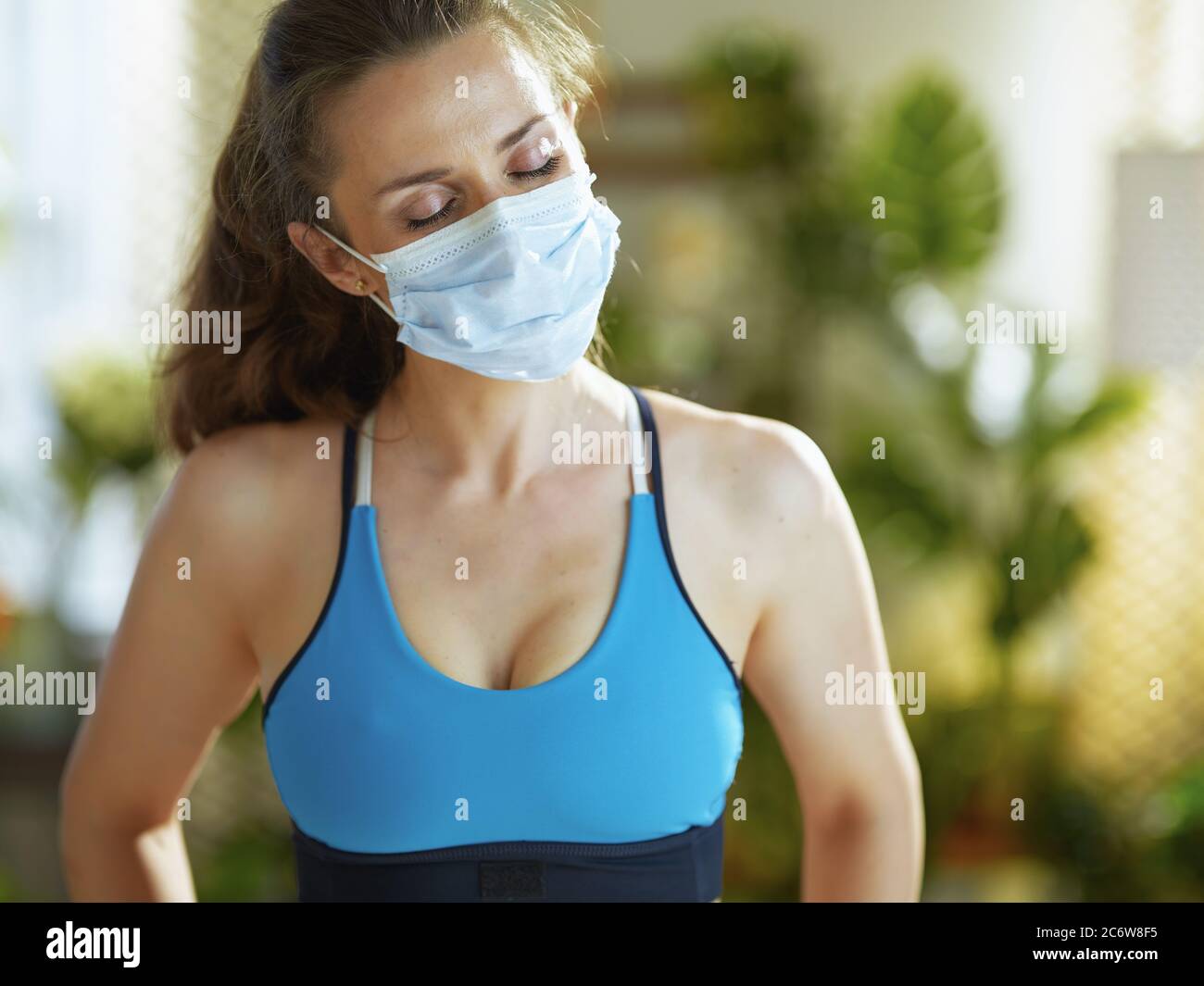 La vida durante la pandemia de covid-19. Mujer sana en ropa de fitness con mascarilla médica. Foto de stock