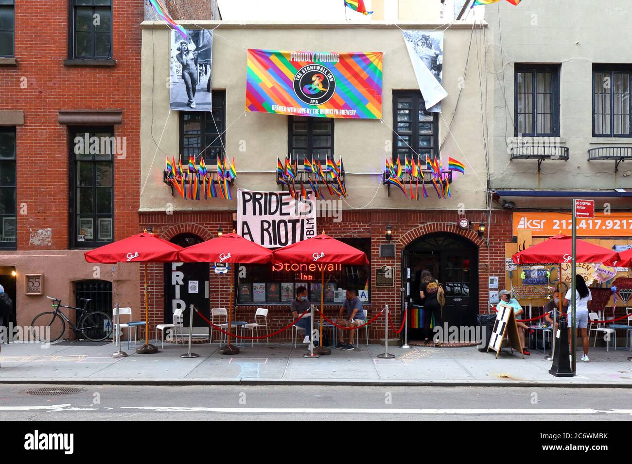 Nueva York. 30 de junio de 2020. Stonewall Inn adornado con unas pocas banderas incluyendo 'Pride is a Riot', y amueblado con asientos al aire libre socialmente distanciados. Foto de stock
