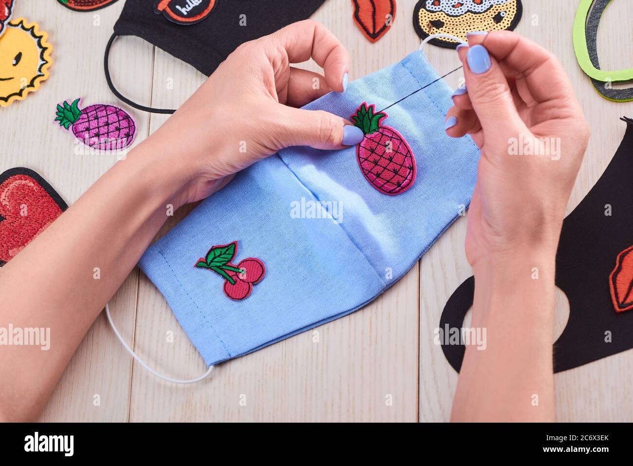 Mujer cosiendo lindos parches bordados en una máscara azul Fotografía de  stock - Alamy