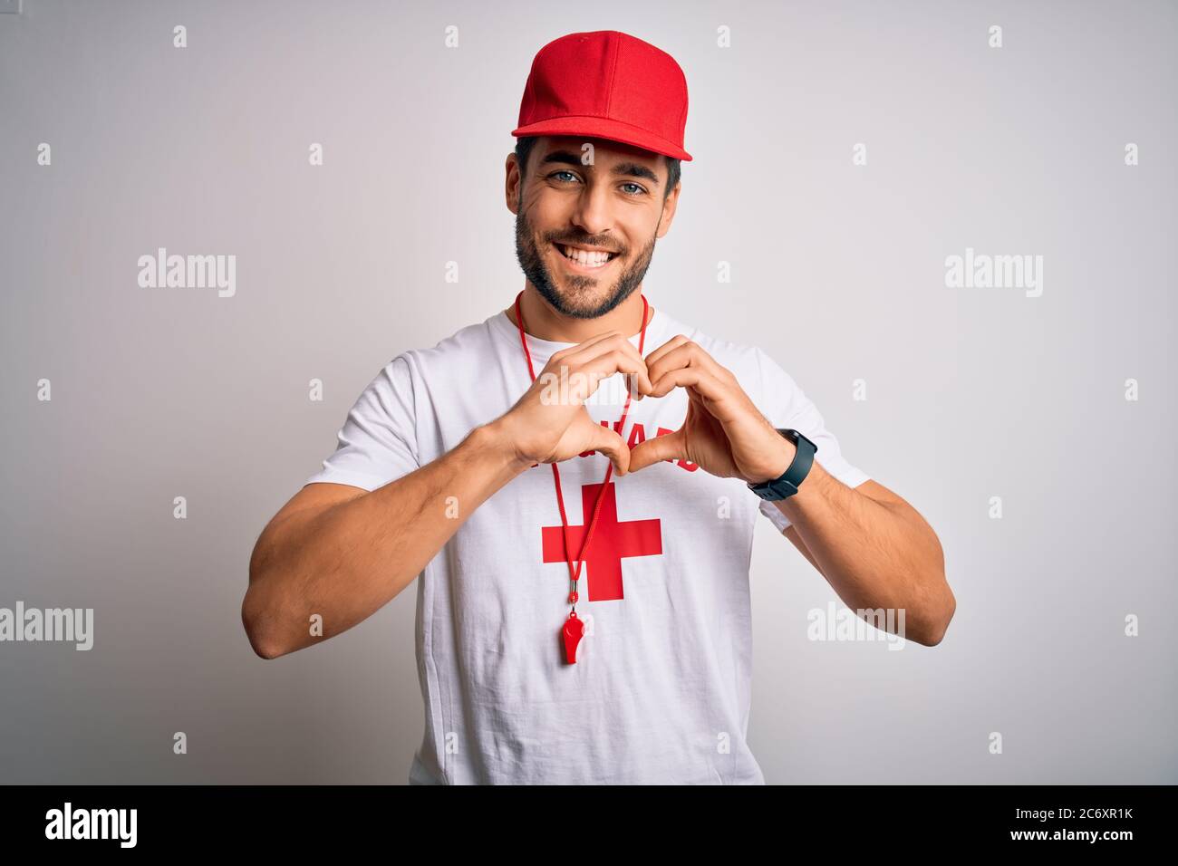 Joven hombre guapo salvavidas con barba con camiseta con cruz roja y  silbato sonriendo en amor mostrando símbolo de corazón y forma con las  manos. Romántico Fotografía de stock - Alamy