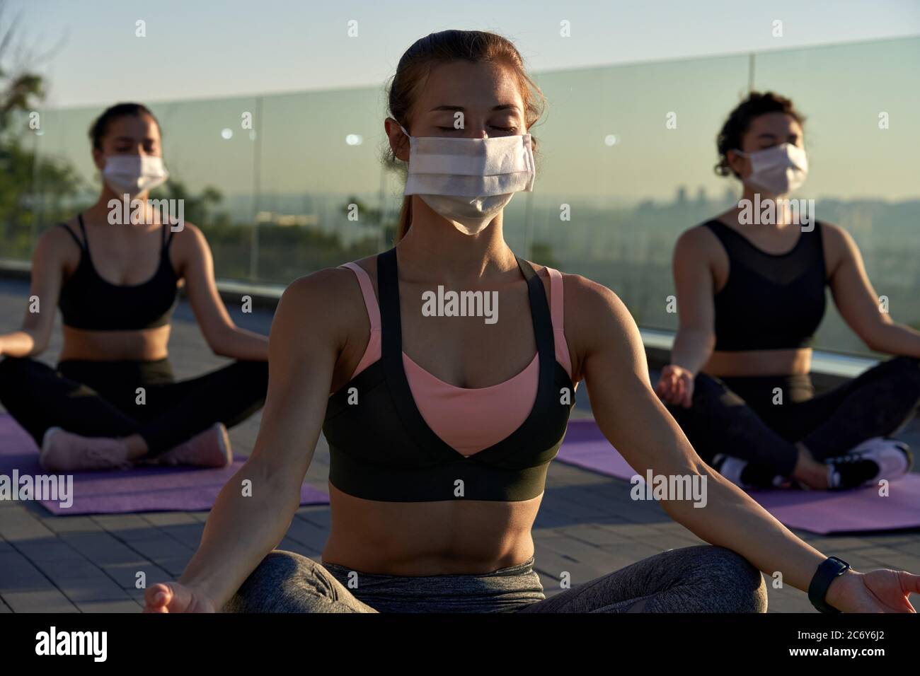 Ajuste deportivo joven mujer llevar máscara meditando mantener la distancia social en la clase de grupo. Foto de stock
