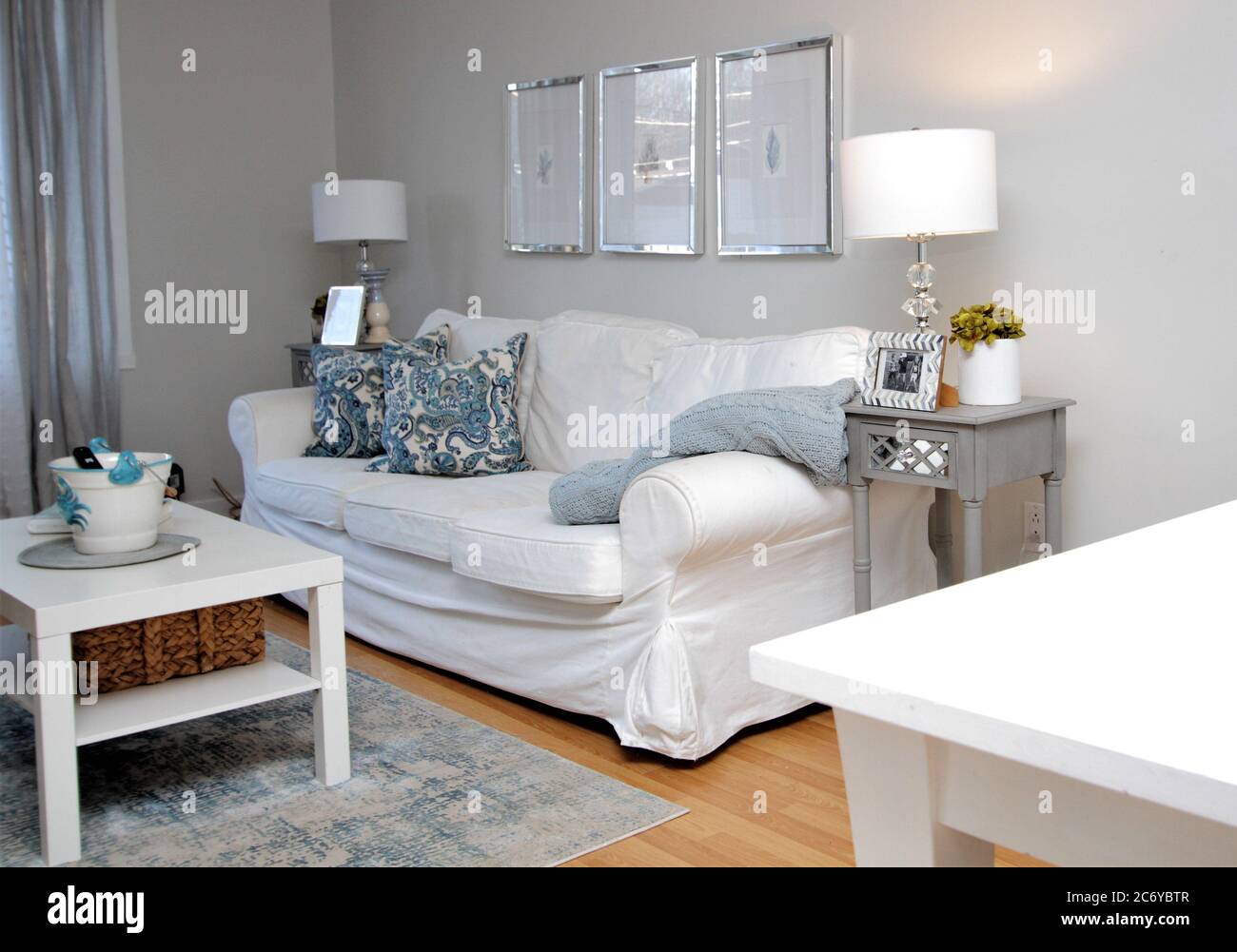Sala de estar decorada en casa de lujo con un elegante sofá blanco, mesa de  café, lámparas, almohadas y mesitas de noche Fotografía de stock - Alamy