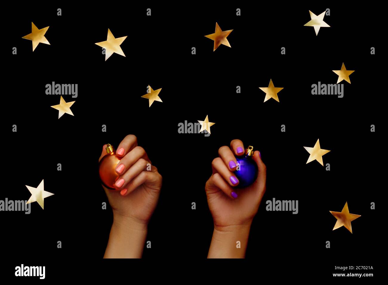Hermosa composición de Navidad. Estrella dorada en la mano con manicura violeta y bolas de Navidad sobre fondo negro. Diseño plano. Espacio de copia. Horizont Foto de stock