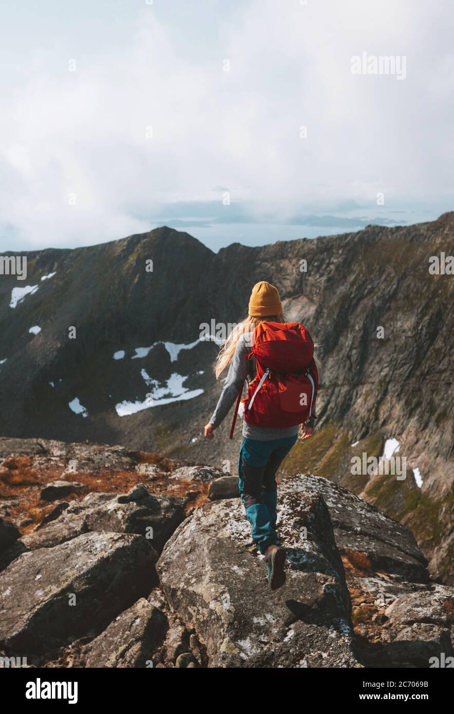 Mujer camino corriendo en las montañas con mochila roja viaje estilo de vida senderismo solo activo vacaciones de verano al aire libre aventura viaje en Noruega Foto de stock