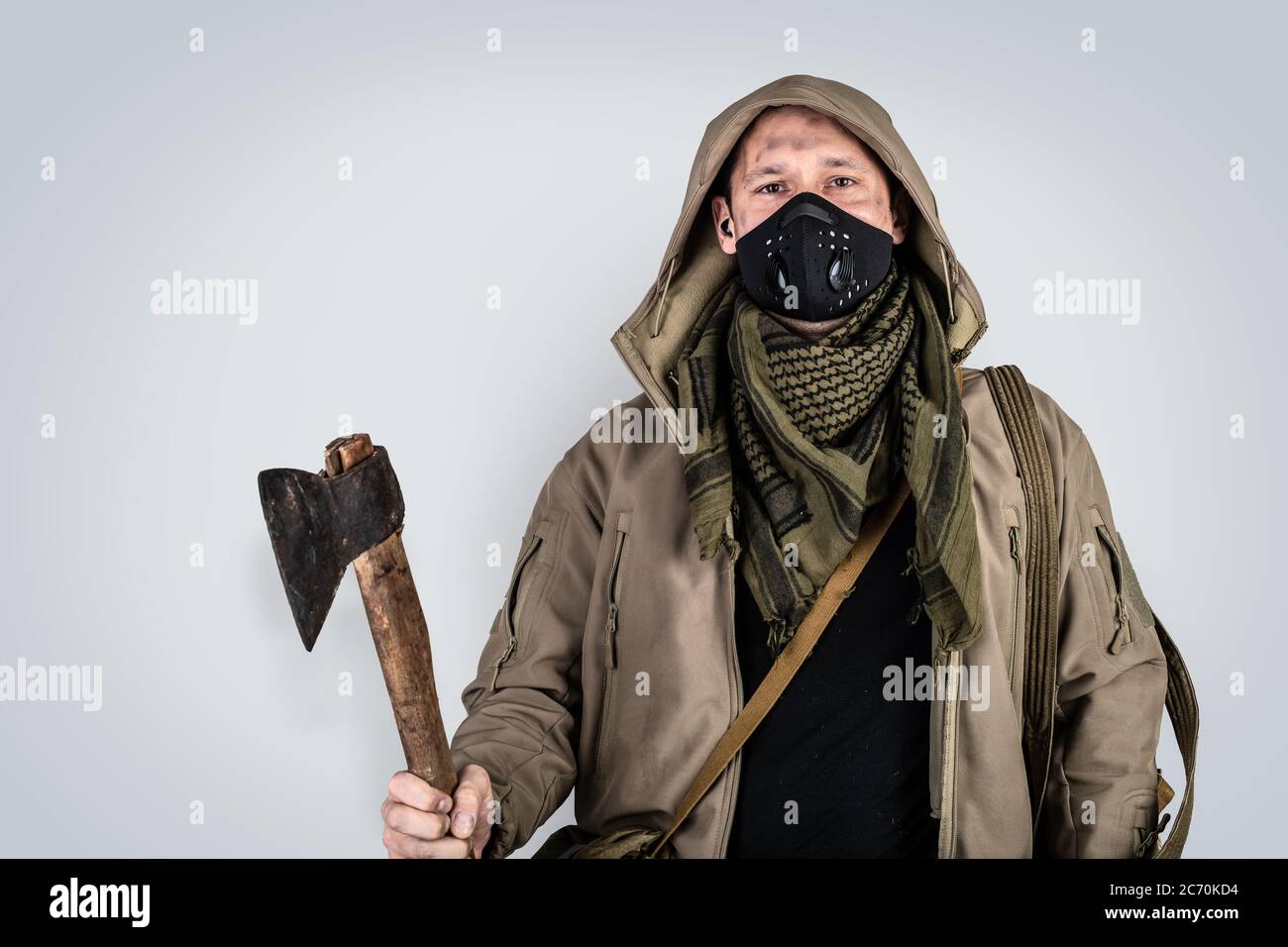 Foto oscura de joven hombre guapo con hacha con máscara de cara protactiva  negra y chaqueta con capucha aislada sobre fondo gris Fotografía de stock -  Alamy