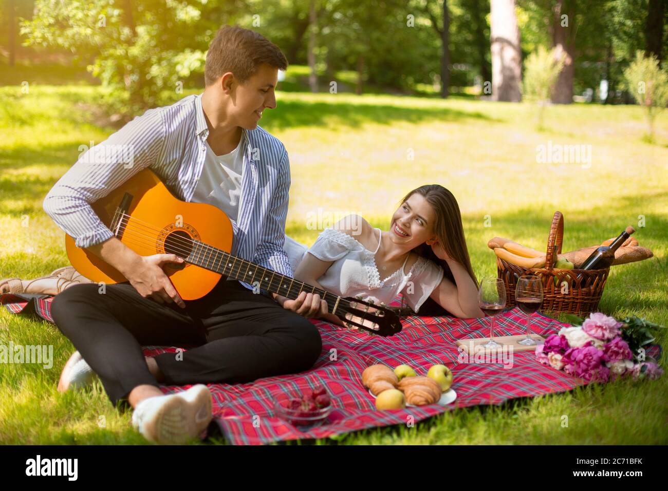 Hombre cariñoso tocando la guitarra y cantando serenata a su novia en un  picnic romántico en el parque Fotografía de stock - Alamy