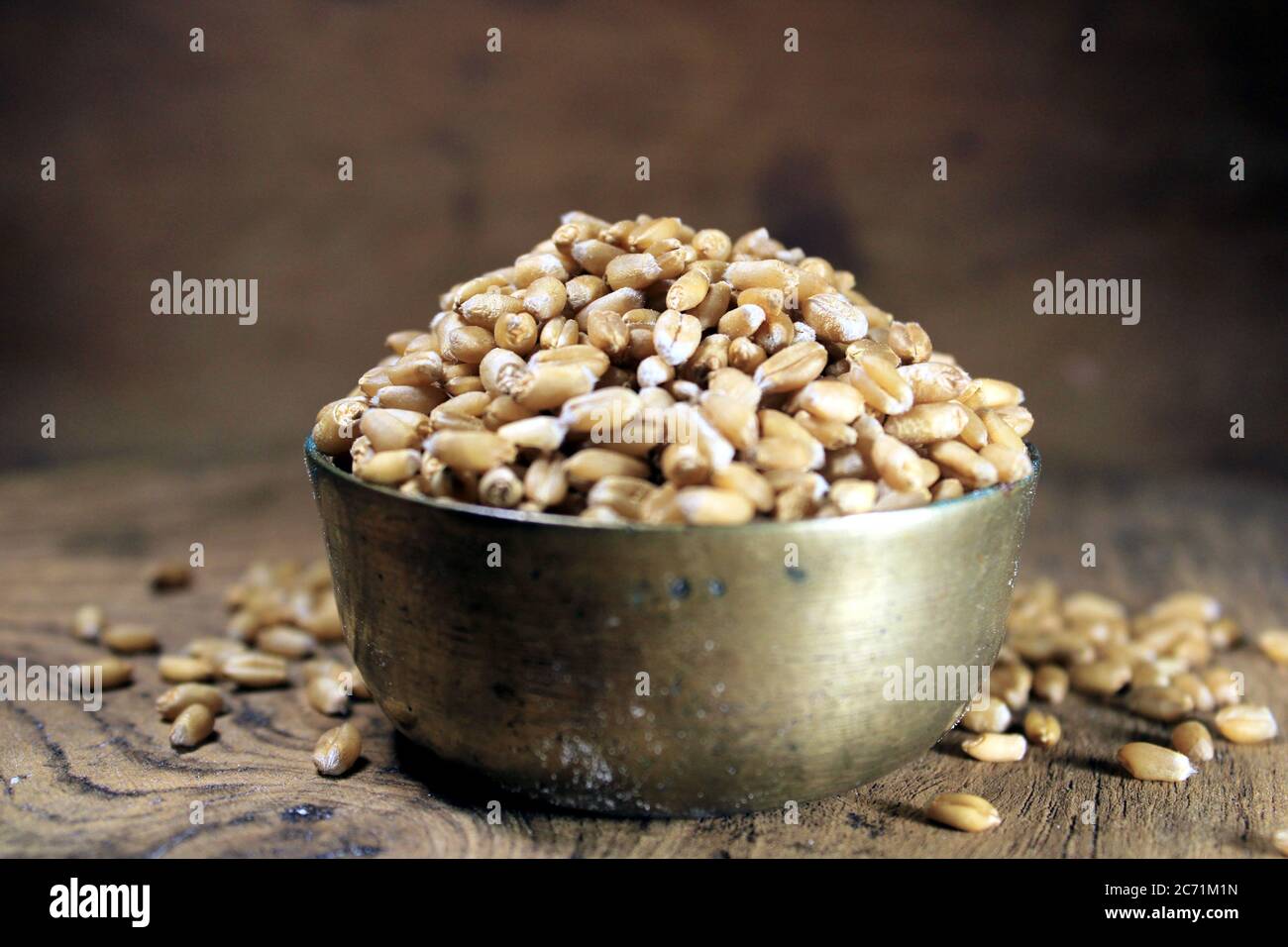 Montón de trigo orgánico de grano entero. Grano de trigo fresco cosechado en un tazón aislado sobre fondo de madera. Granos de trigo y harina de trigo. Foto de stock