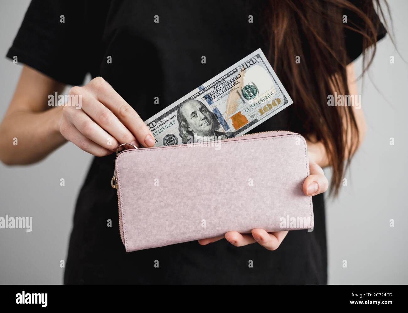 Una joven saca billetes de dinero en dólares de una cartera. De cerca Foto de stock