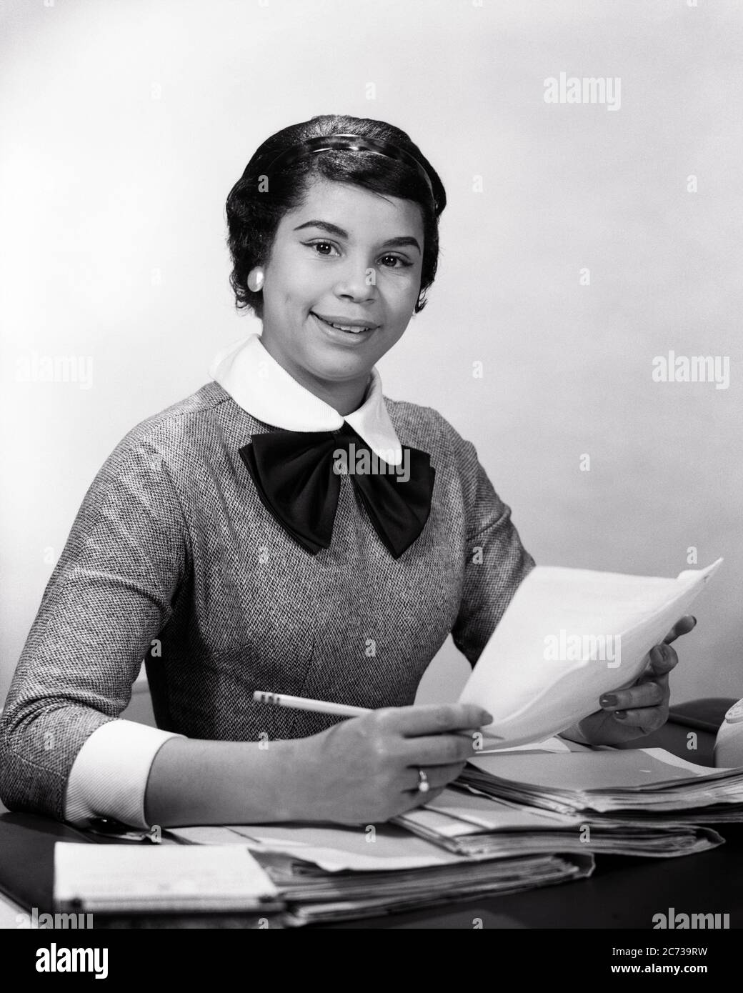 1950S 1960 SONRIENTE MUJER AFROAMERICANA SECRETARIA EN EL ESCRITORIO SOSTENIENDO PAPELES LÁPIZ MIRANDO LA CÁMARA - N177 HAR001 HARS ESTILO PROFESORES COMUNICACIÓN CARRERA PAPELEO INFORMACIÓN ASISTENTE ALEGRÍA ALEGRÍA ESTILO DE VIDA SATISFACCIÓN EMPLEADO MUJERES TRABAJOS STUDIO SHOT MANAGER COPIAR ESPACIO DE MEDIA LONGITUD SEÑORAS PERSONAS PENDIENTES PROFESIÓN CONFIANZA EJECUTIVOS DE MEDIANA EDAD B&W EMPRESARIA CONTACTO VISUAL ARCHIVOS CUELLO BLANCO HABILIDAD OCUPACIÓN DOCUMENTOS FELICIDAD HABILIDADES ALEGRE SERVICIO AL CLIENTE AFRO-AMERICANOS CARRERAS INSTRUCTOR NEGRO ETNIA ORGULLO OFICINA OCUPACIONES TRABAJADORES SONRISAS GAL VIERNES Foto de stock