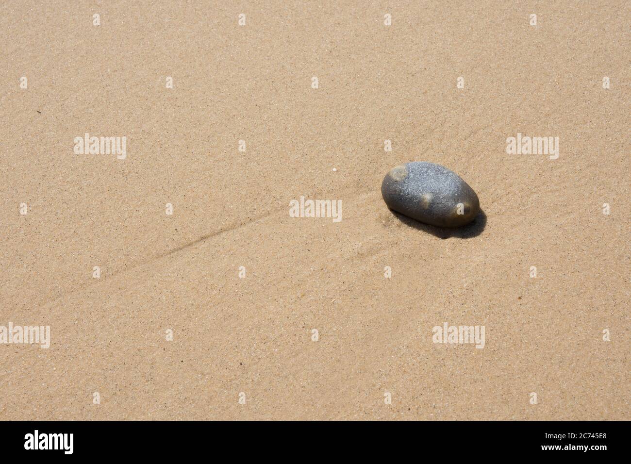 Una sola playa suave guijarros contra un fondo de arena suave lavada por agua Foto de stock