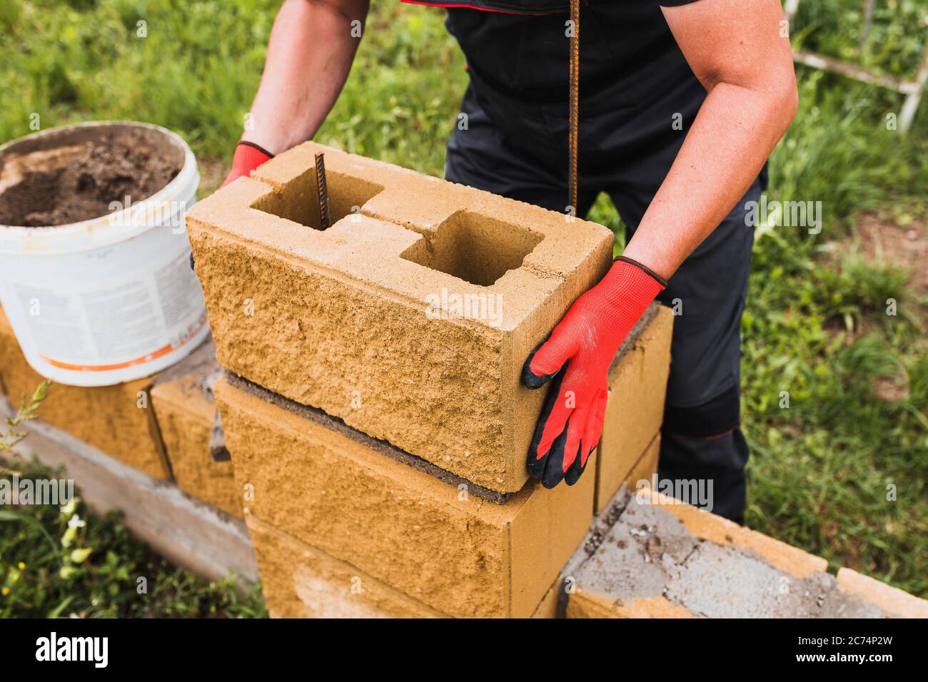 El trabajo duro de un constructor - un profesional de ladrillo hábilmente construye paredes de ladrillo y bloque de concreto Foto de stock