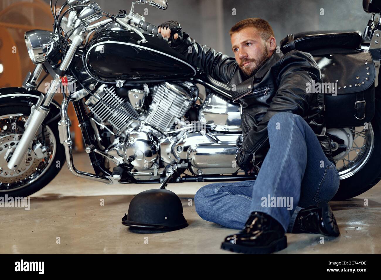 Motociclista barbudo con ropa de negro con moto Fotografía de stock -
