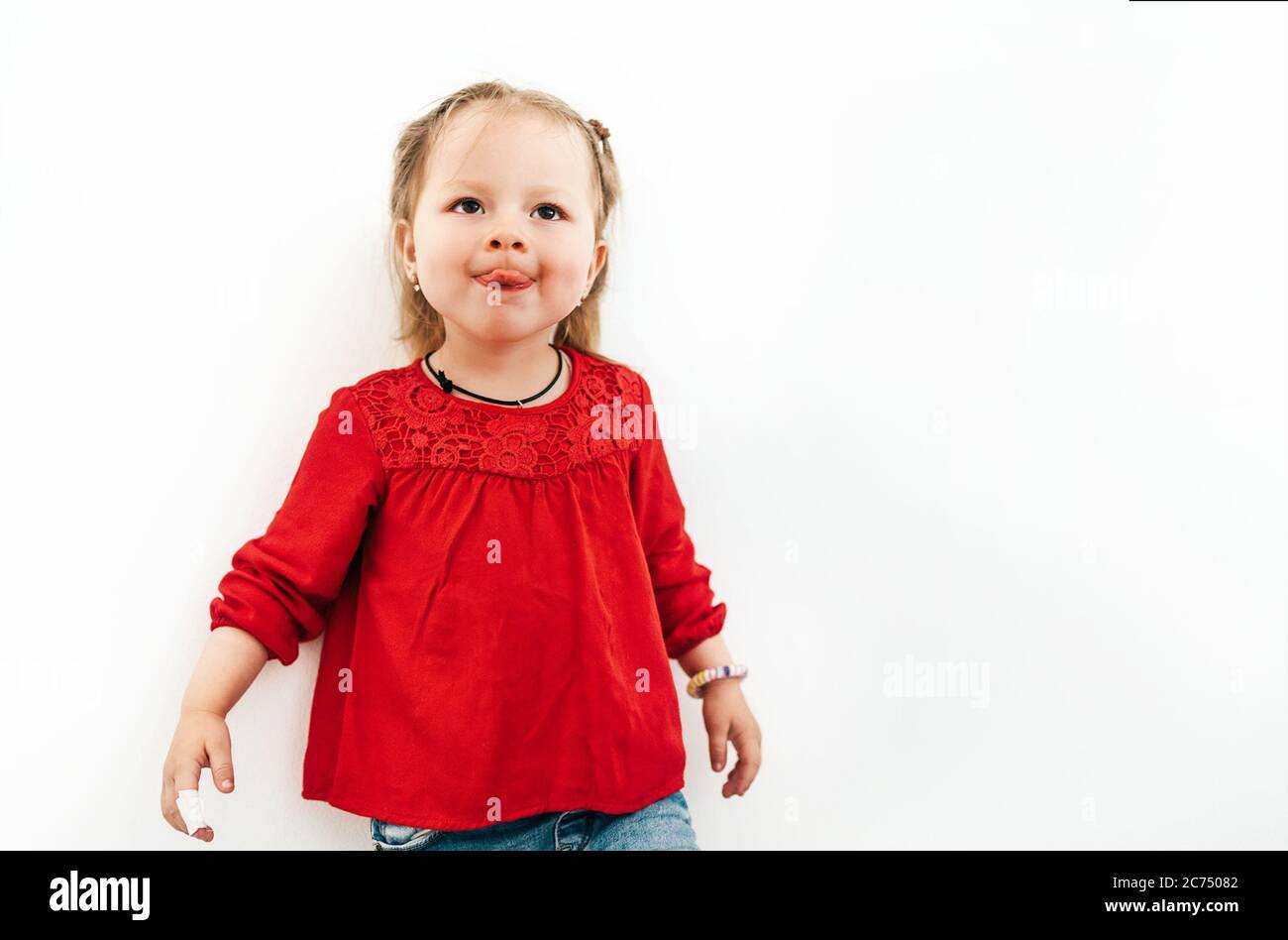 Feliz niña emocional en blusa roja mostrando lengua. Blanco fondo de  estudio de grabación Fotografía de stock - Alamy