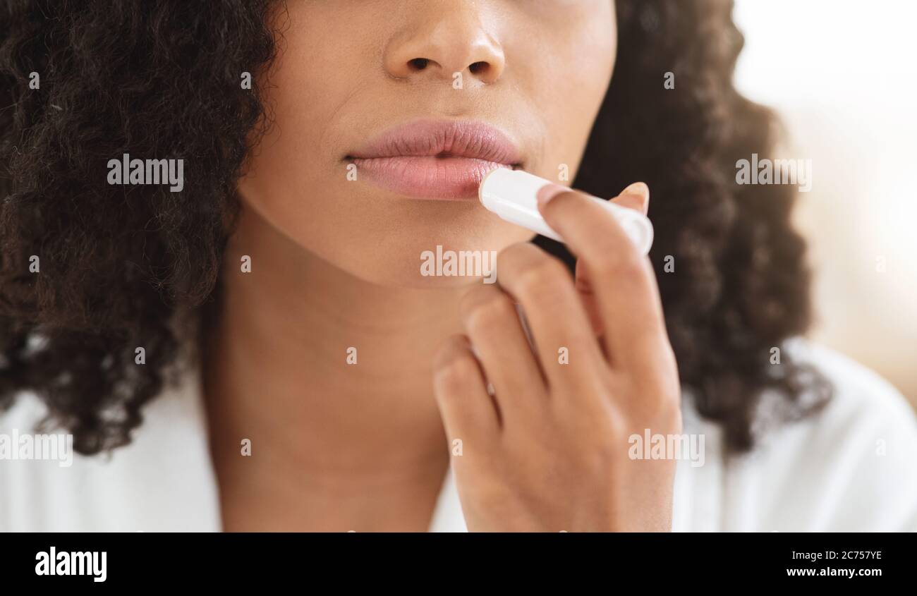 Labios agrietados remedios. Primer plano de la mujer negra aplicando Chapstick labio de moisturizing bálsamo Foto de stock