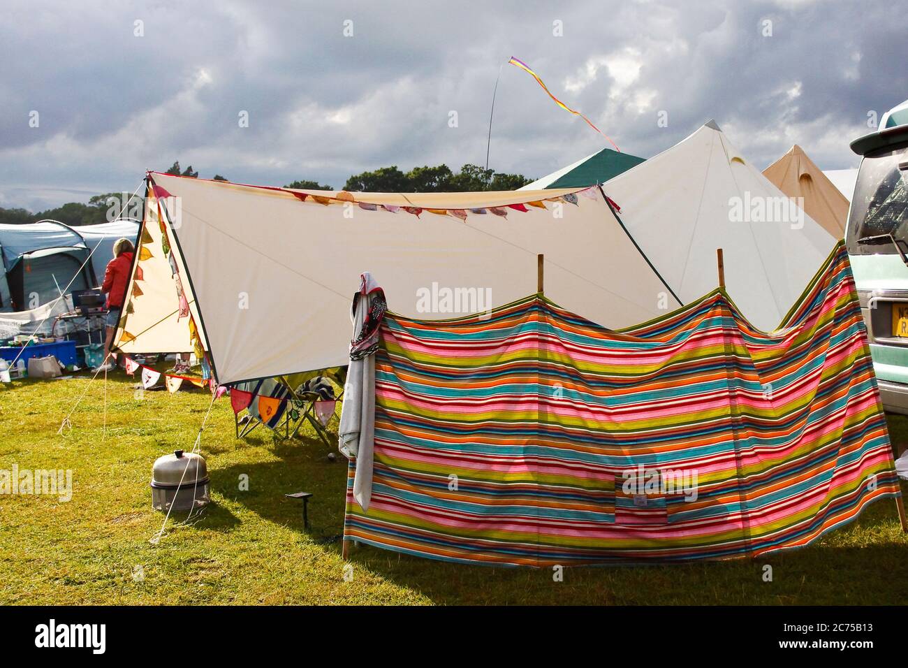 Colorido y espelido camping cortavientos para sombra con bunting y nubes de lluvia tormenta en un festival de camping en Norfolk Fotografía stock - Alamy