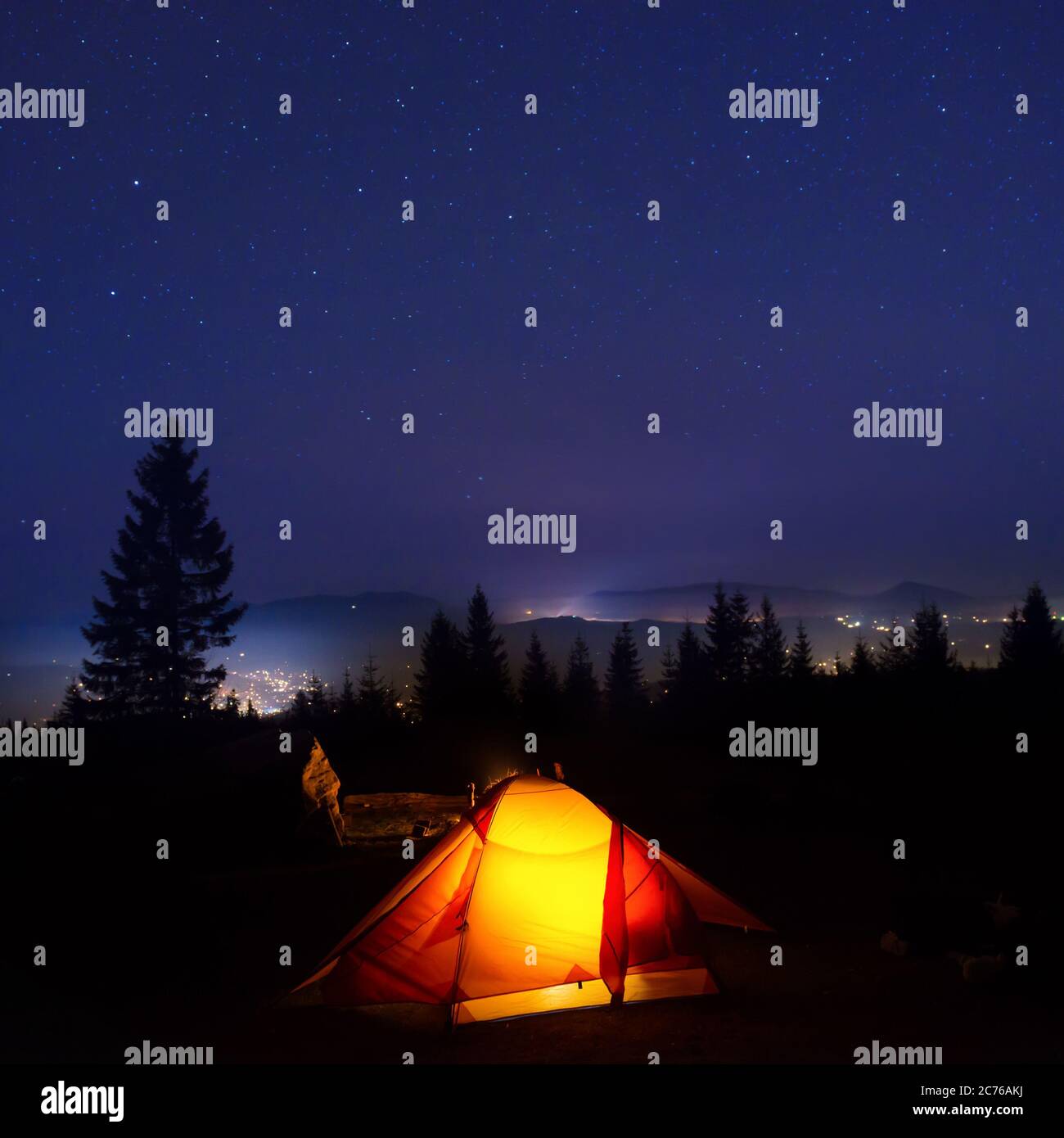 Iluminado en naranja camping carpa bajo la luna, las estrellas en la noche Foto de stock