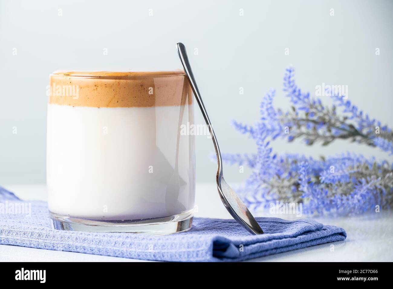 Café Dalgona. Una copa de leche de moda en una servilleta azul. Foto de stock
