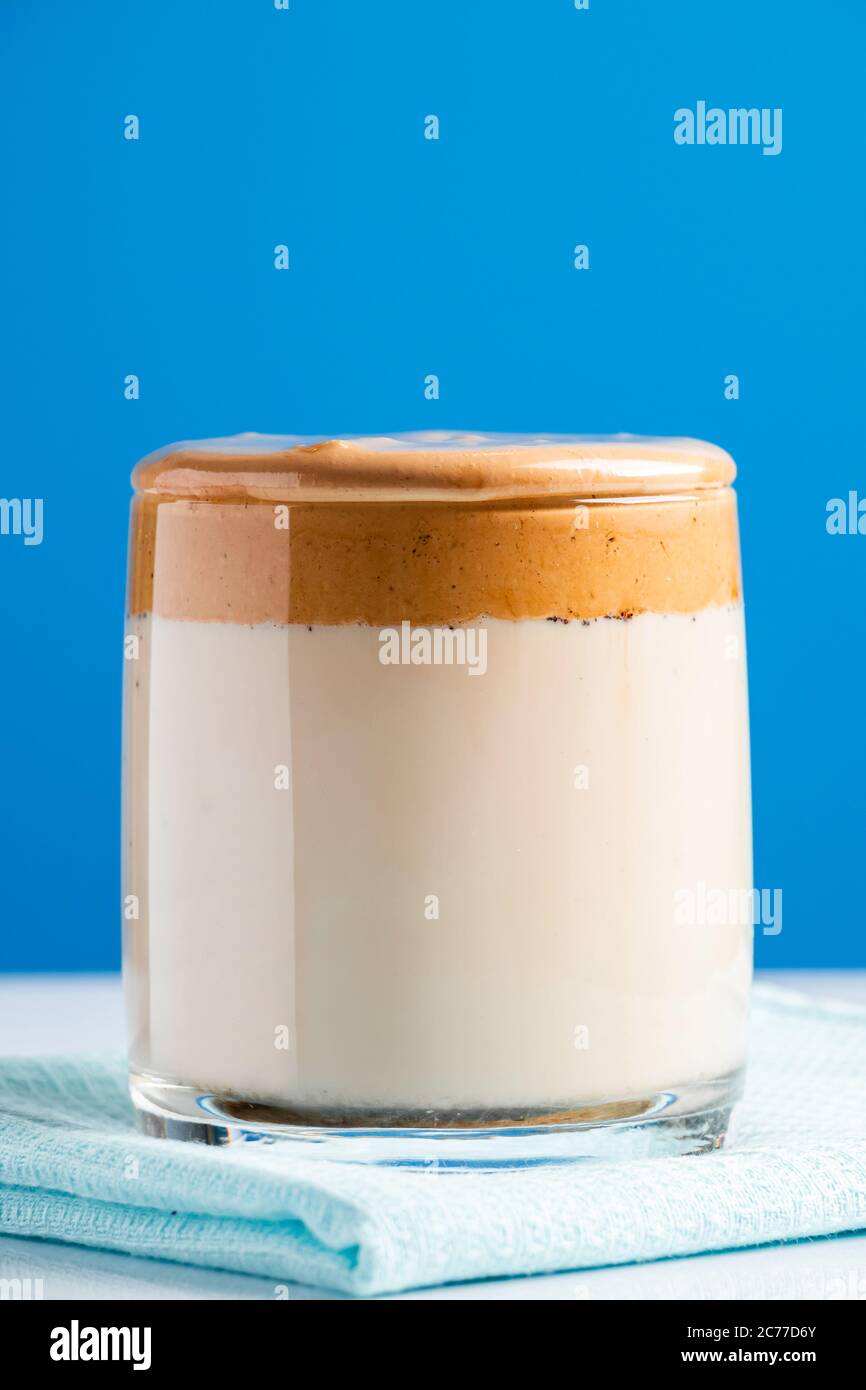 Café de Dalgona sobre fondo azul. Moda tendencia bebida de leche y espumas batidas dulces. Foto vertical Foto de stock