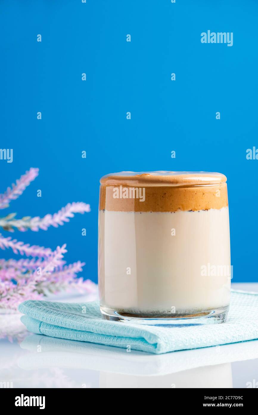 Café de Dalgona sobre fondo azul. Bebida de tendencia de moda de leche y espumas batidas dulces. Foto vertical Foto de stock