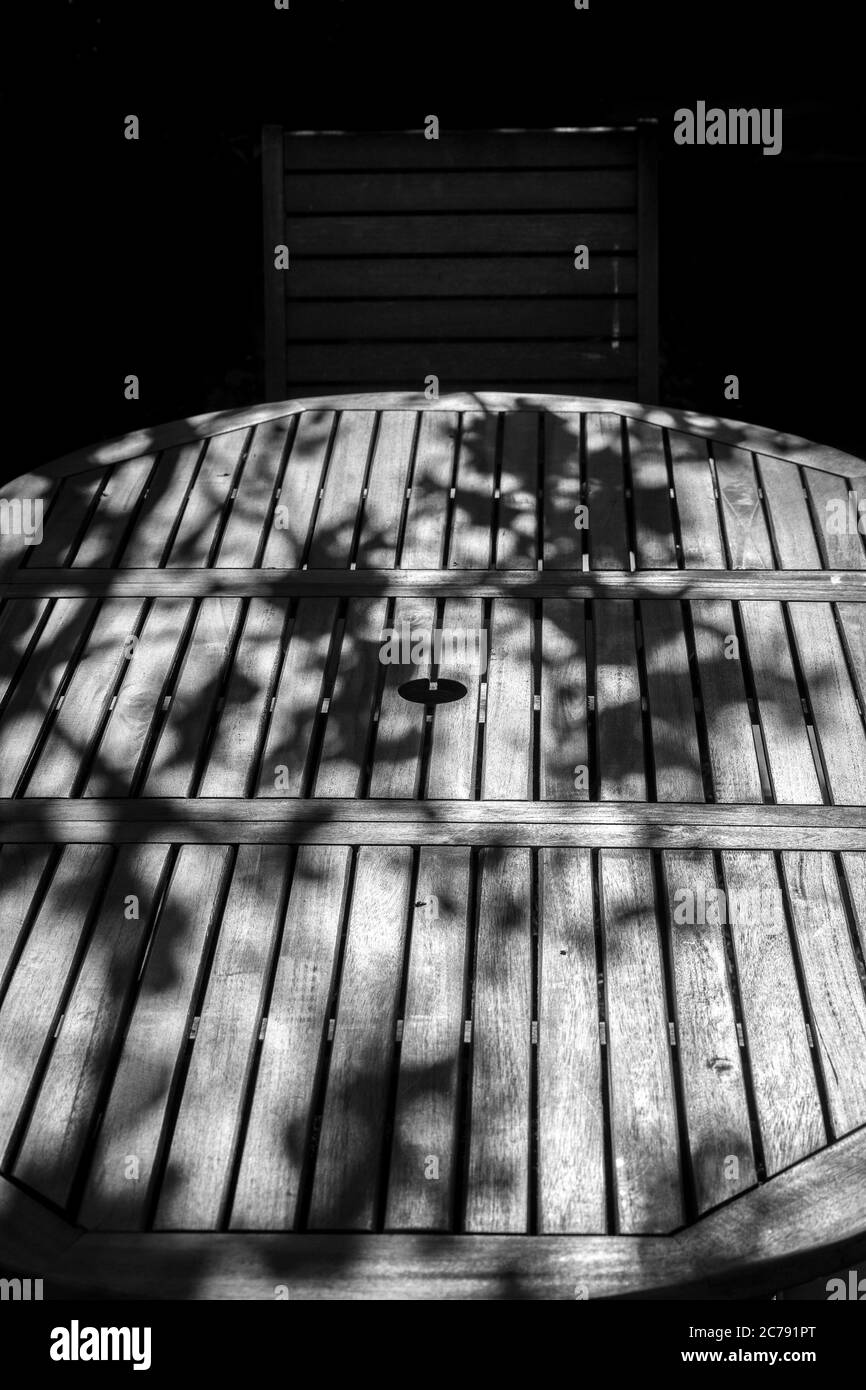 las ramas dejan sombras sobre la mesa de madera del jardín, Foto de stock