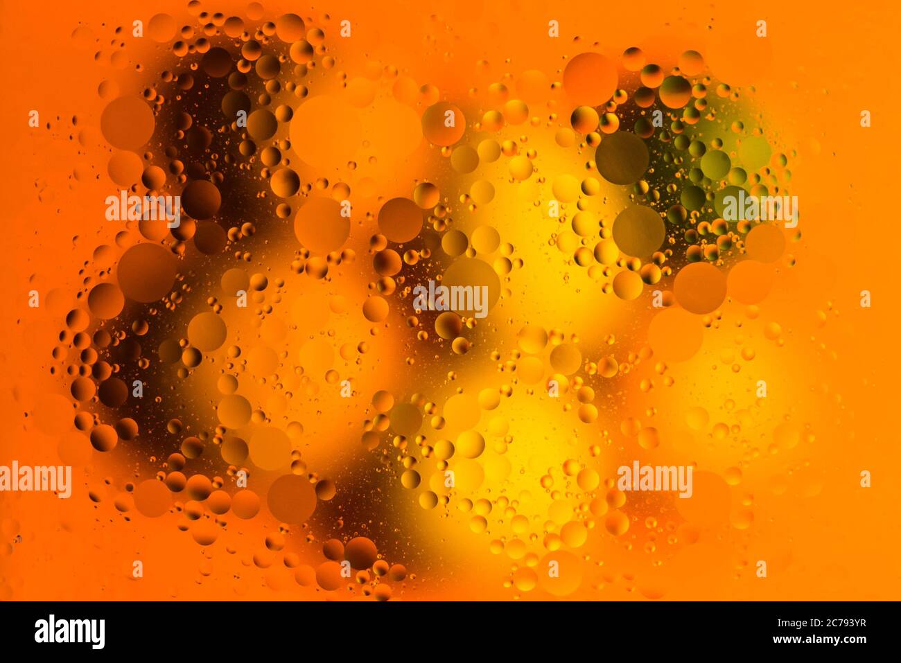Estudio de primer plano imagen de gotas de aceite sobre el agua sobre un fondo de color naranja Foto de stock