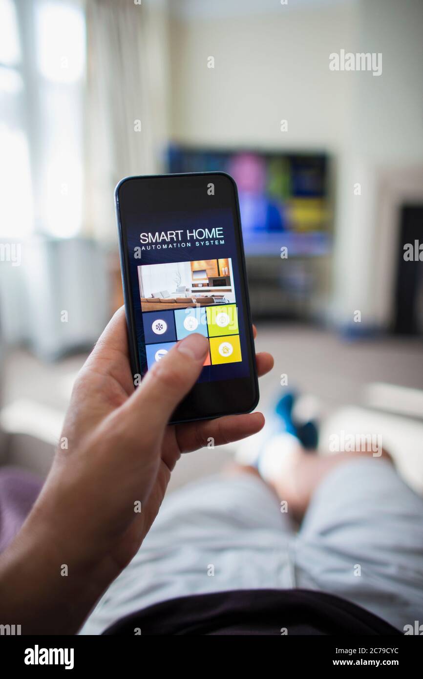 POV Man uso de la automatización en casa en el teléfono inteligente en la sala de estar Foto de stock
