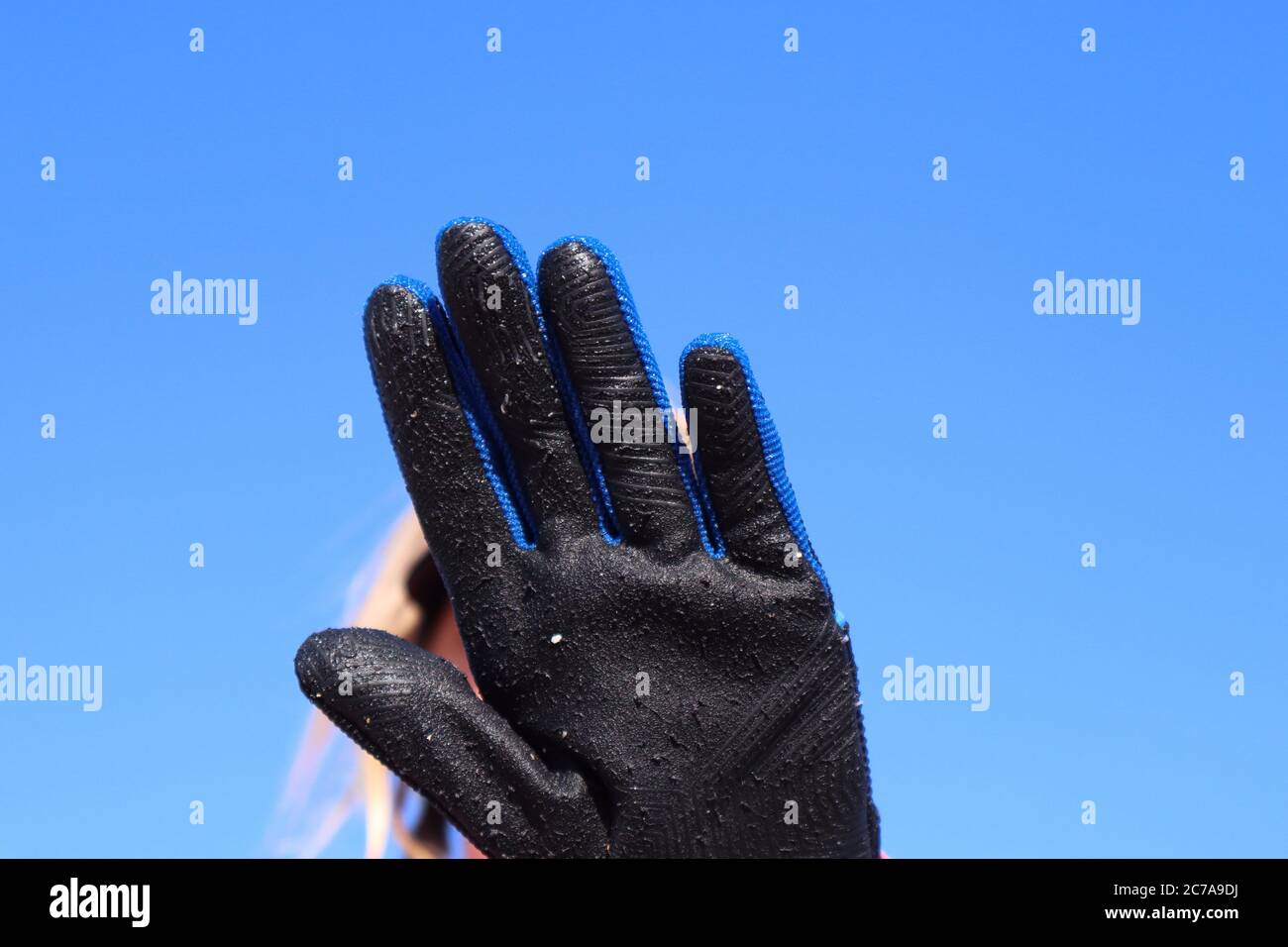 mano enguantada para deportes acuáticos gesto mojado de parada contra el cielo azul. Foto de alta calidad Foto de stock