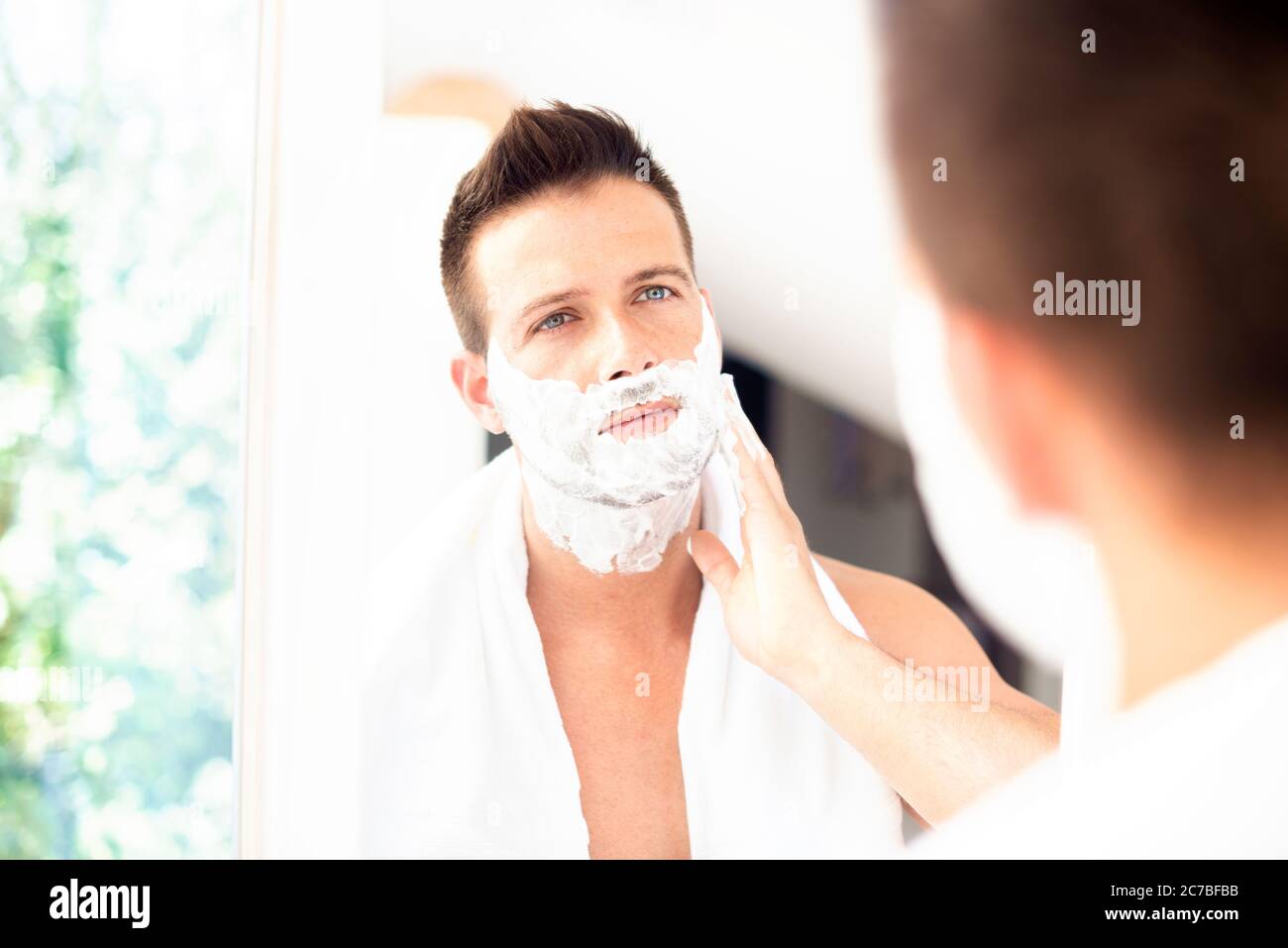 Un hombre se afeita frente a un espejo espuma de afeitar maquinilla de  afeitar desechable