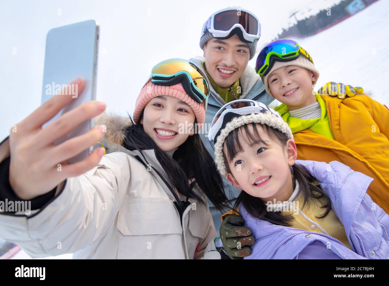 Esquiar en una familia de cuatro se abrazan juntos Foto de stock