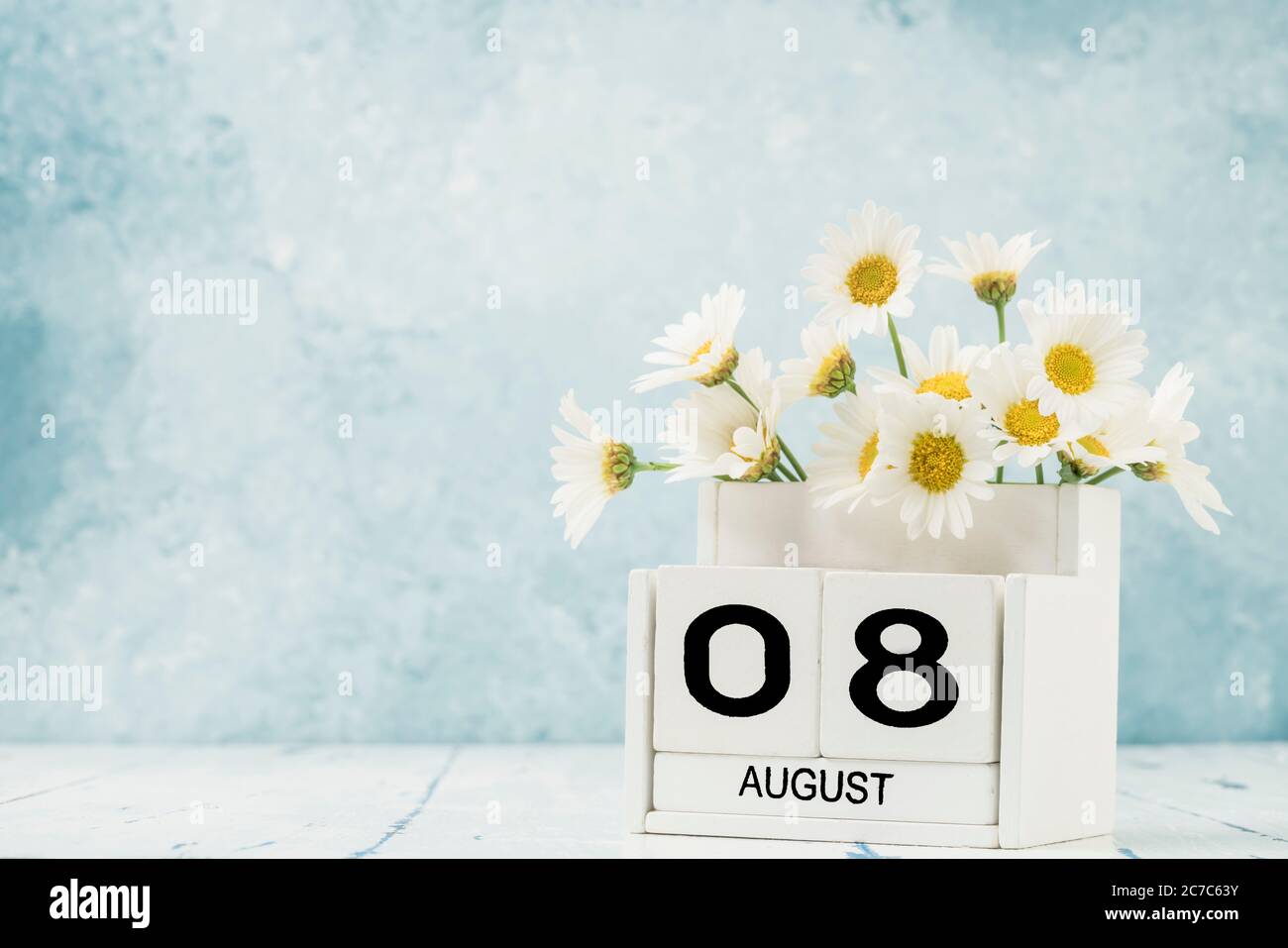 Calendario cubo blanco para agosto decorado con flores margaritas encima  fondo azul con espacio de copia Fotografía de stock - Alamy