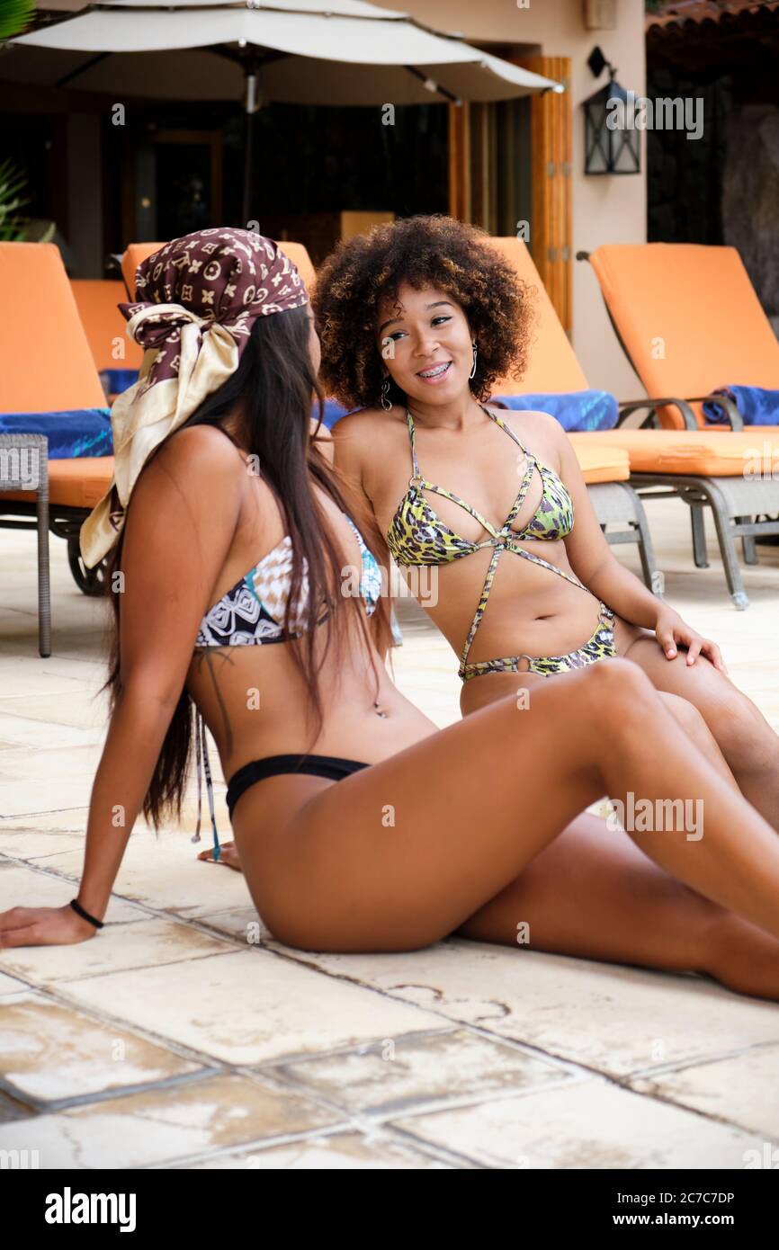 Día de vacaciones en México - 2 mujeres jóvenes disfrutando de una conversación en una piscina Foto de stock