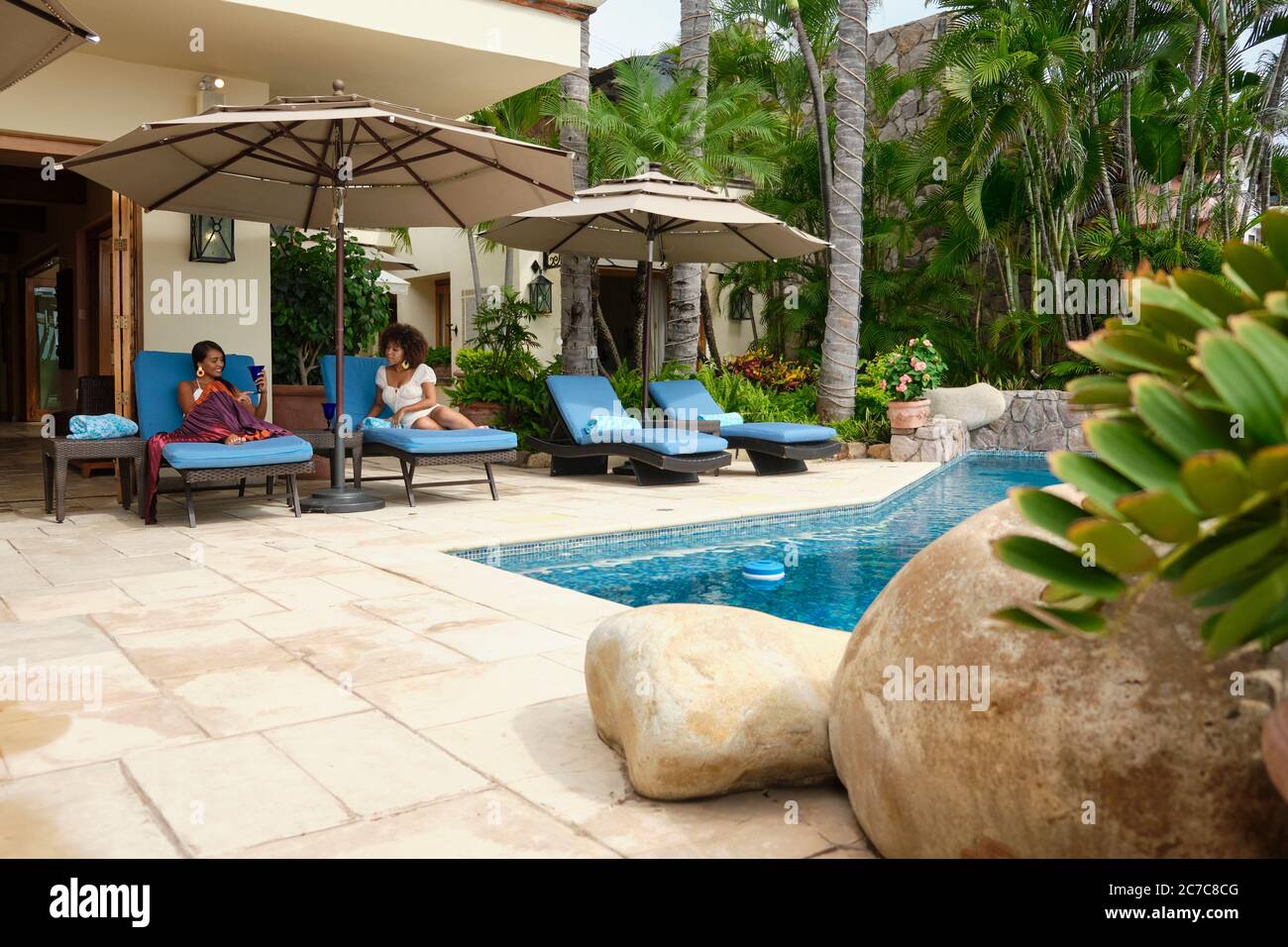 Descansando en la piscina - 2 mujeres disfrutando de una estancia en una villa de vacaciones, Puerto Vallarta, Jalisco, México Foto de stock