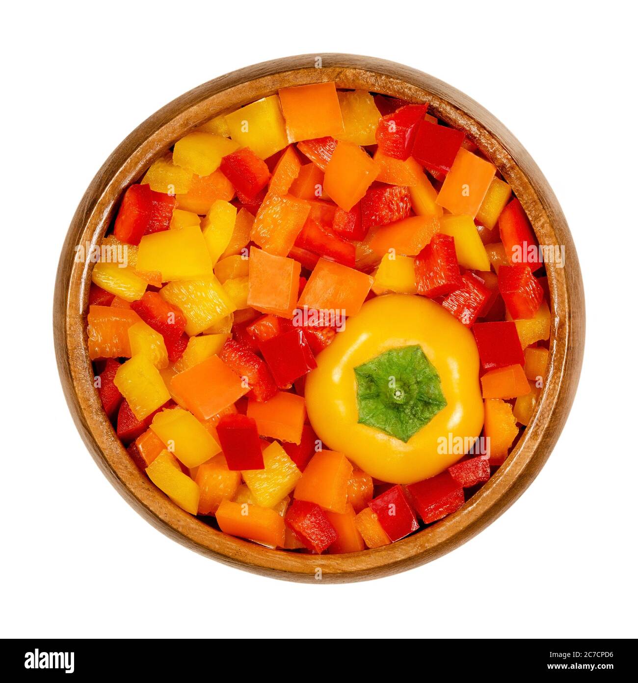 Cabeza de pimiento y vainas cortadas en un tazón de madera. Pimiento dulce, capsicum, también pimentón, cortado en chips de colores. Frutas frescas amarillas, naranjas y rojas. Foto de stock