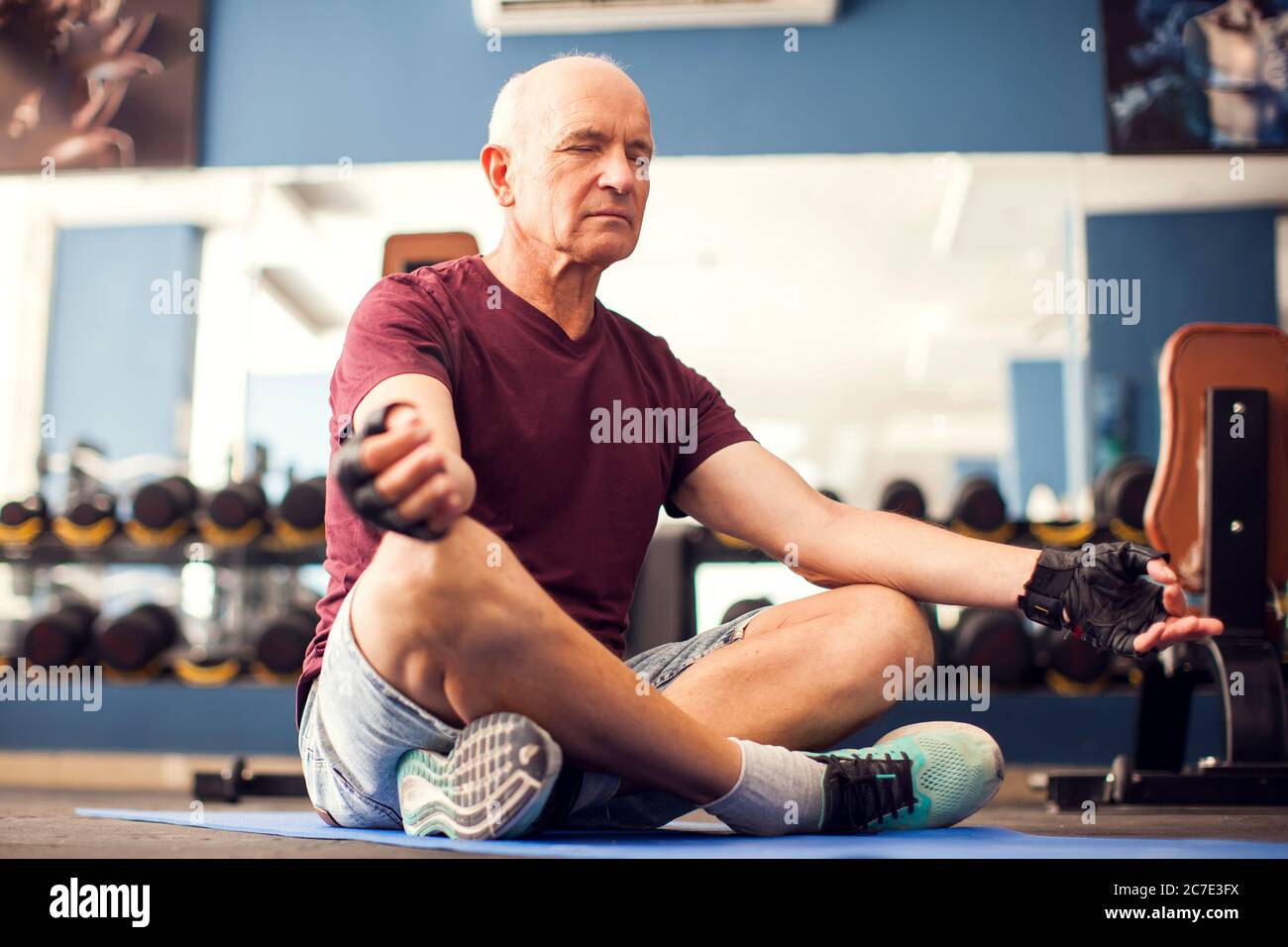 Un retrato de un hombre mayor calvo haciendo ejercicio de relajación en el gimnasio. Personas, salud y estilo de vida Foto de stock
