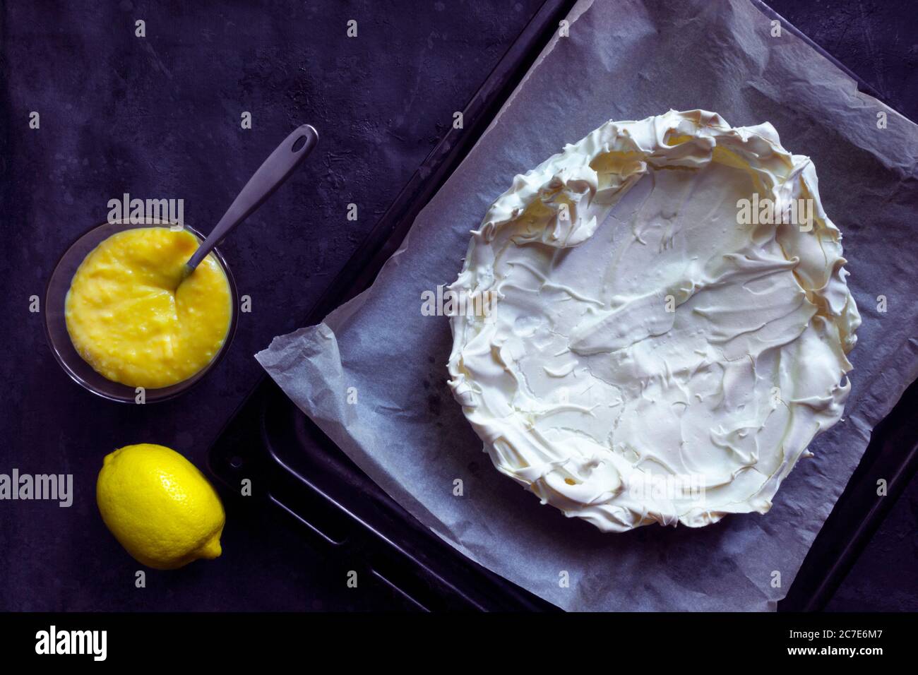 Merengue casero base para pastel Pavlova con limón curd. Postre crujiente sobre fondo negro Foto de stock