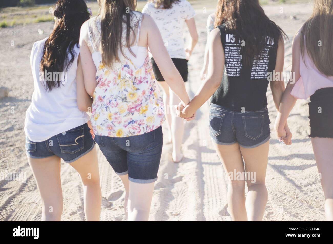 Tiro horizontal de seis chicas adolescentes con pantalones cortos y  caminando en la arena mientras se sostiene las manos Fotografía de stock -  Alamy