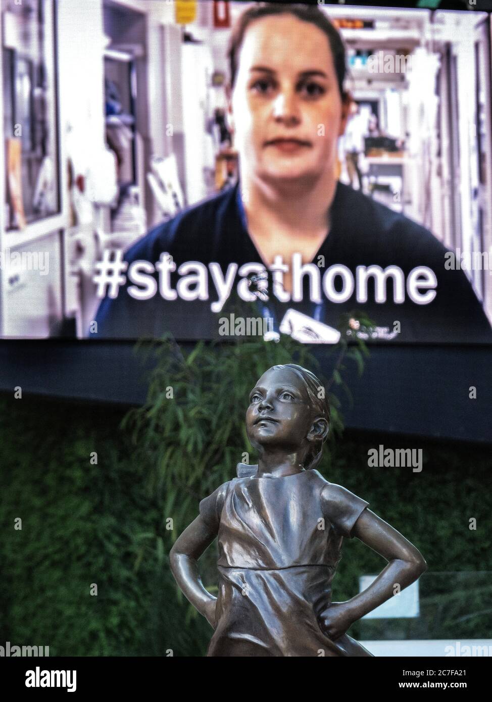 Melbourne Australia pandemia de Covid-19. La estatua de la Niña temible se encuentra ante la campaña publicitaria electrónica de la cartelera #stayathome en Federation Square. Foto de stock