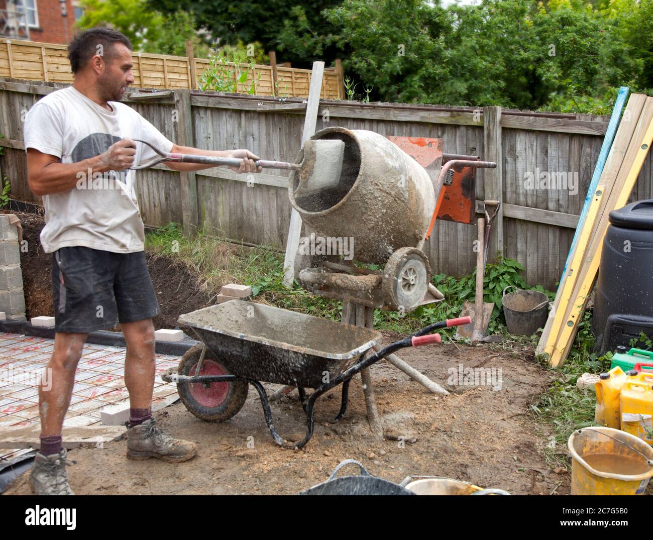 Un constructor que carga un mezclador de cemento con una pala y una  carretilla Fotografía de stock - Alamy