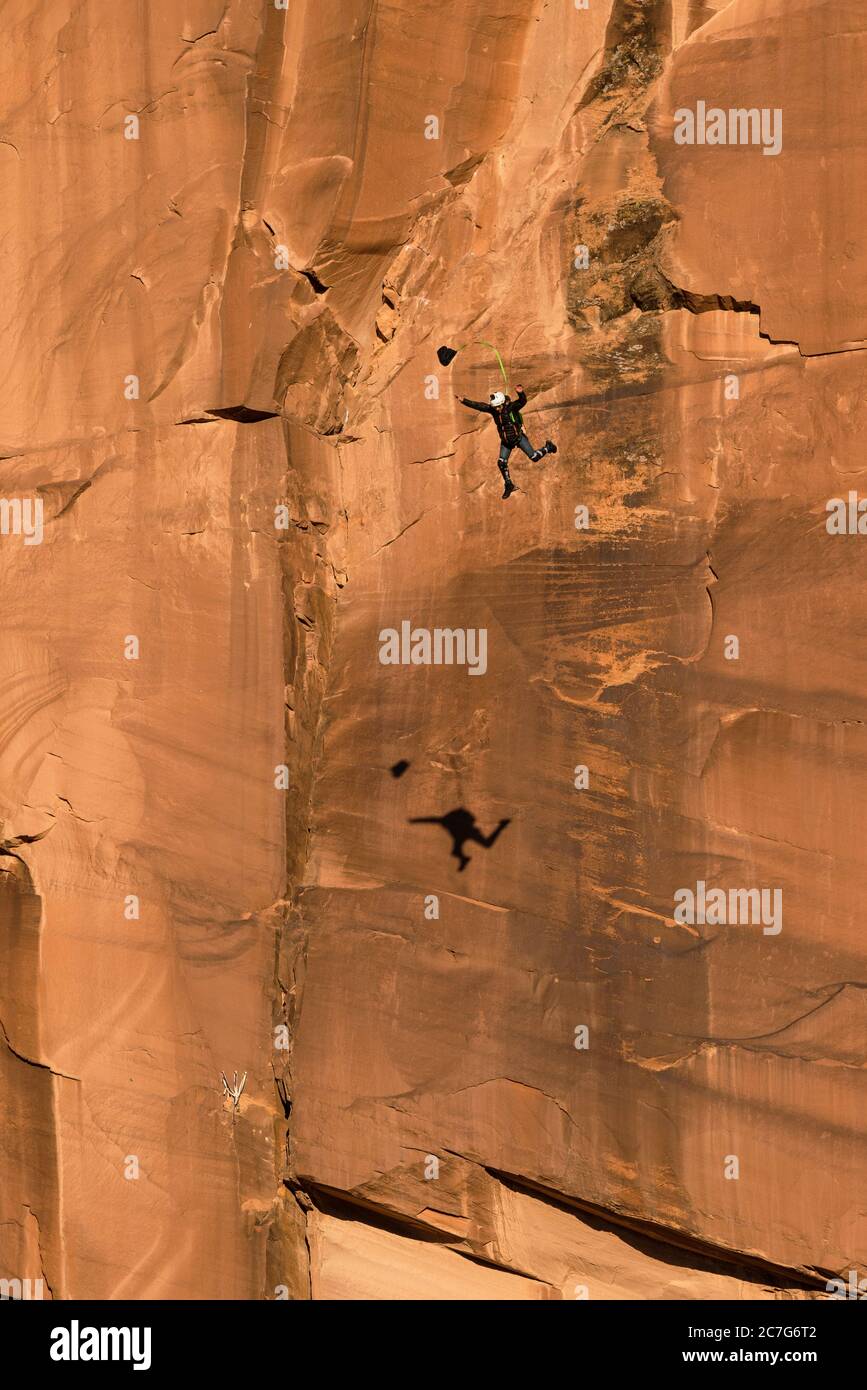 Usa, Utah, Moab, un puente base salta de la cara vertical de 400 pies de Tombstone en Kane Springs Canyon. Ha desplegado su canal piloto. Observe su sombra en el acantilado. Foto de stock