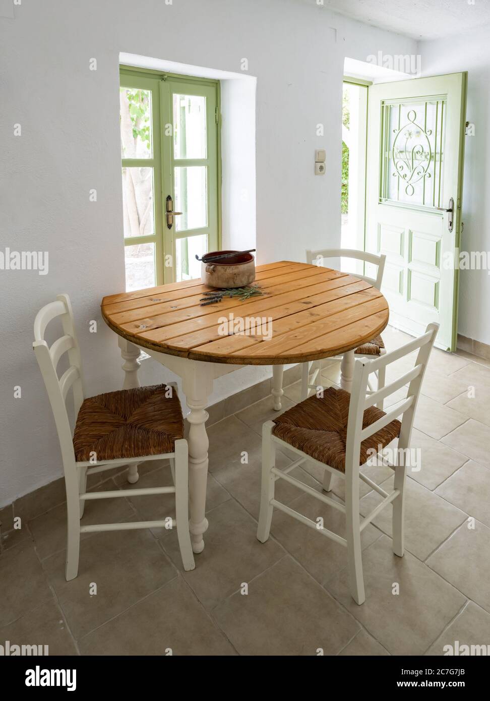 bisonte Converger datos Una mesa de cocina blanca sencilla con superficie de madera y sillas blancas  en una casa de campo con puerta y ventana al jardín Fotografía de stock -  Alamy