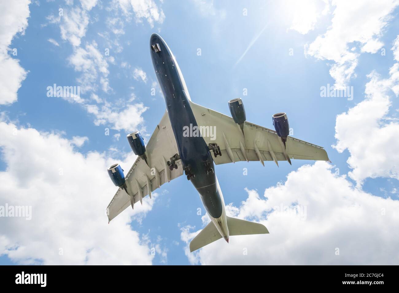 el sol detrás de un gran avión de pasajeros en el aterrizaje se aproxima a un aeropuerto con su tren de aterrizaje abajo Foto de stock