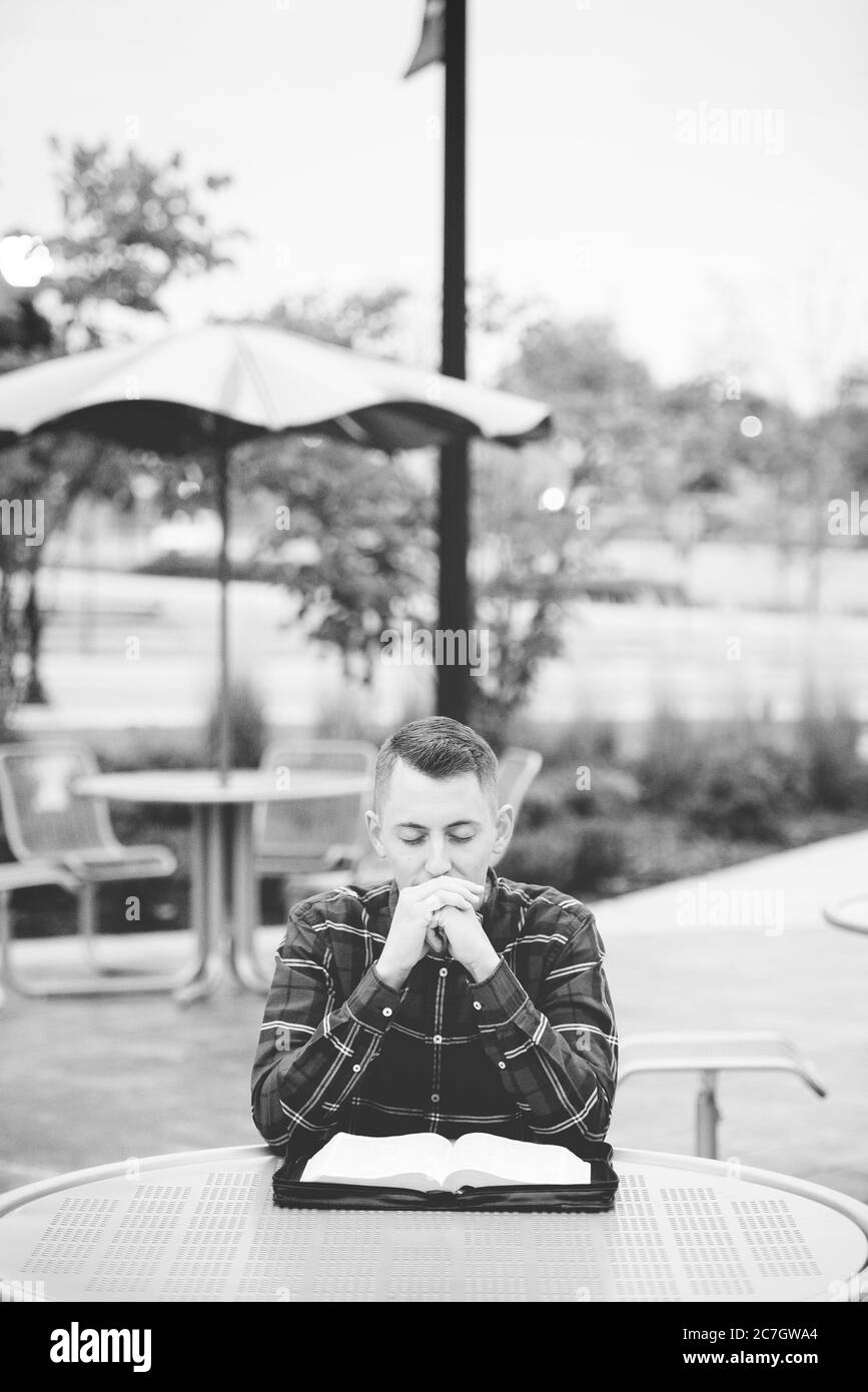 Tiro en escala gris vertical de una persona sentada a una mesa con un